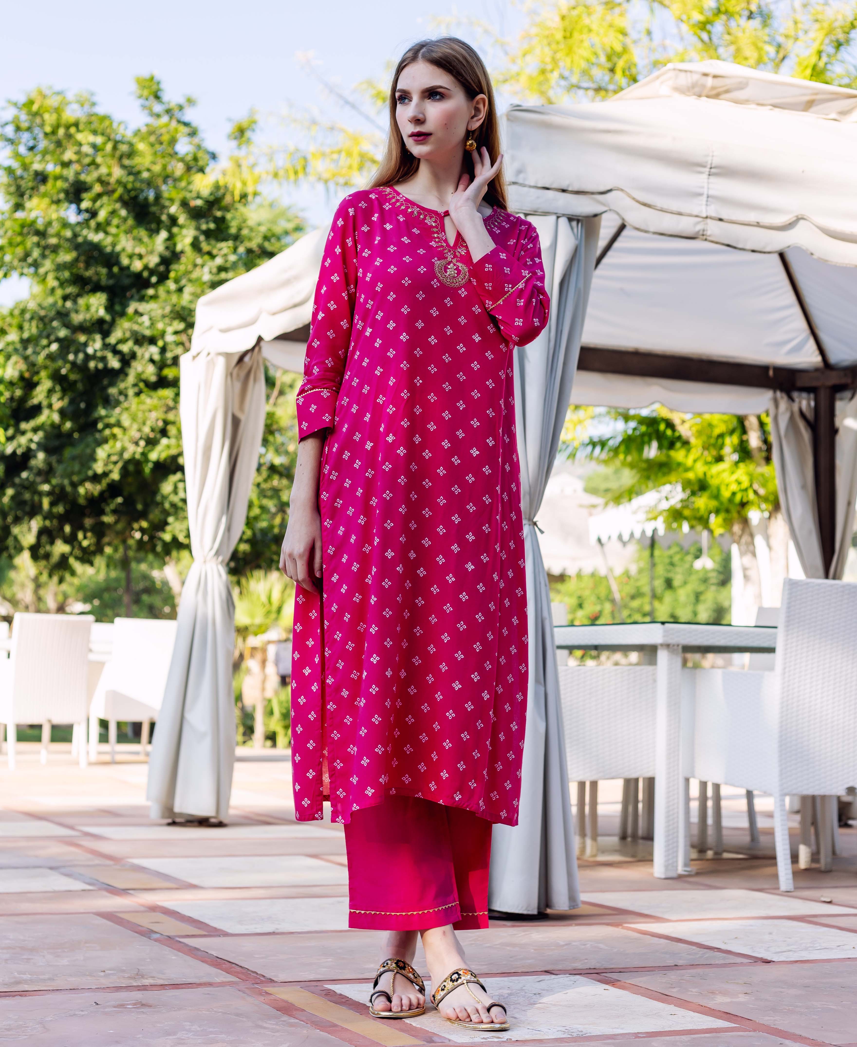 Full body shot of a model wearing a magenta block printed kurta set with embroidered neckline.