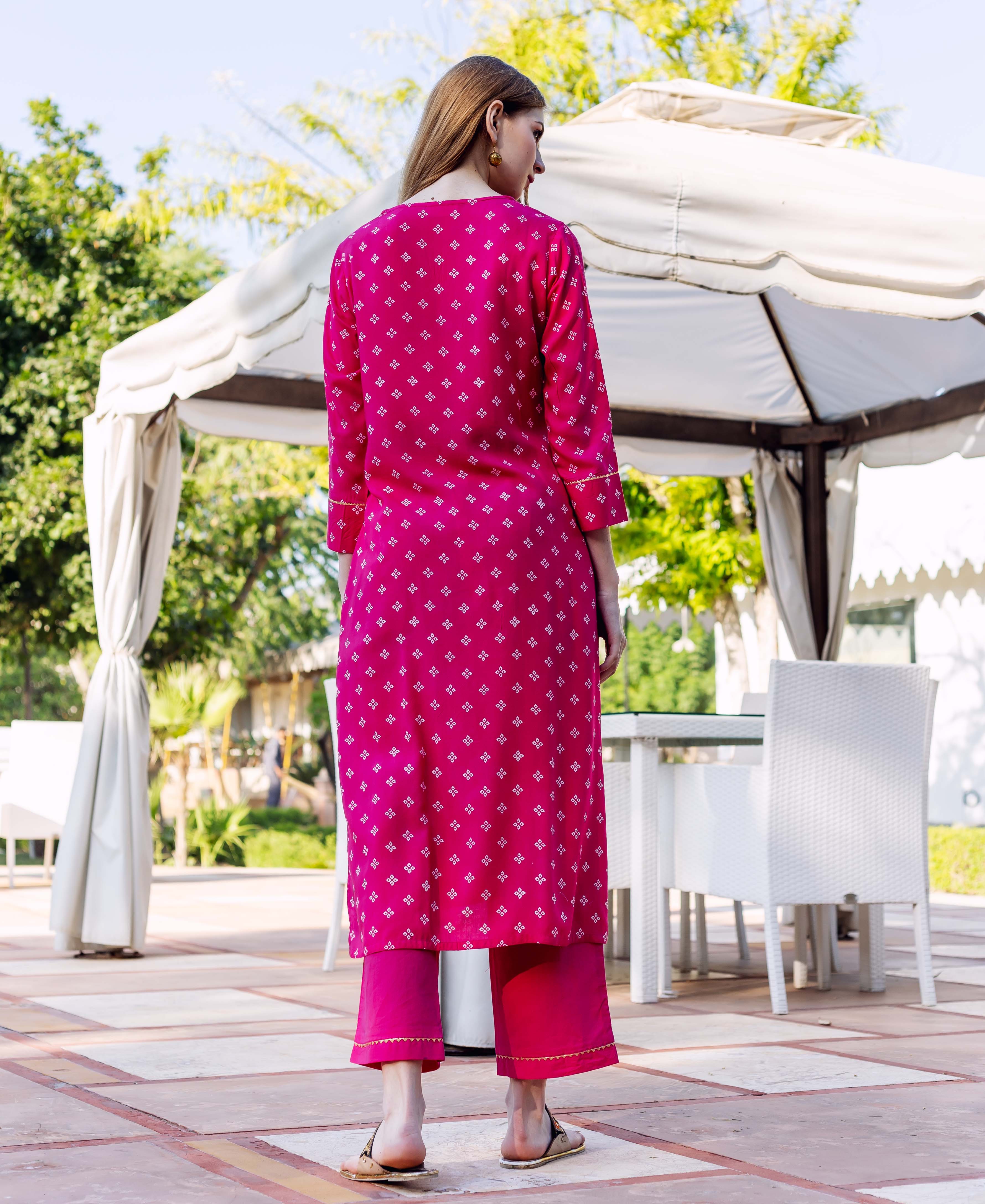 Rear view of a model wearing a magenta kurta set with small white geometric print.