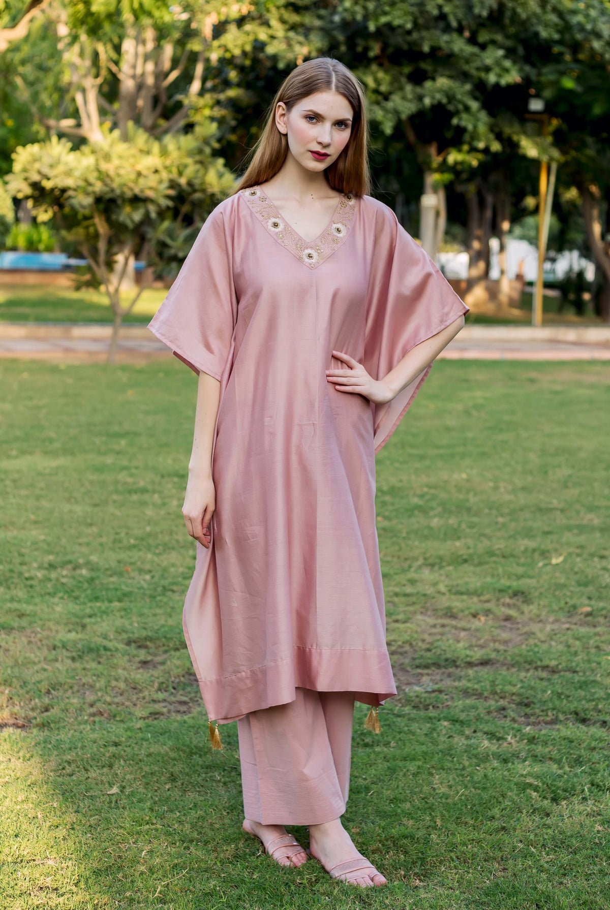 Front view of a model in a dusty pink hand-embroidered kaftan and matching pants.