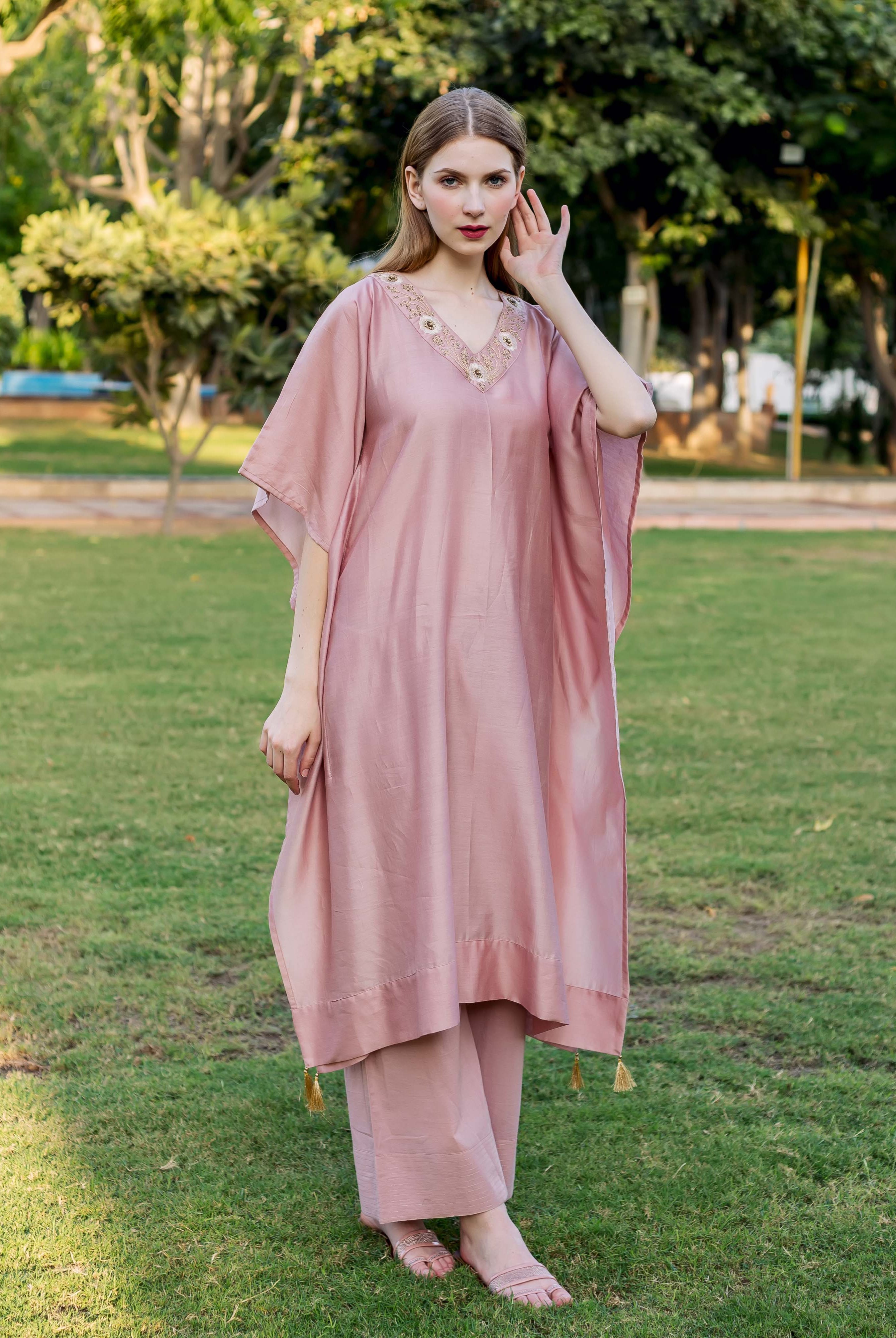 Full-length shot of a model wearing a dusty pink hand-embroidered kaftan and matching pants.