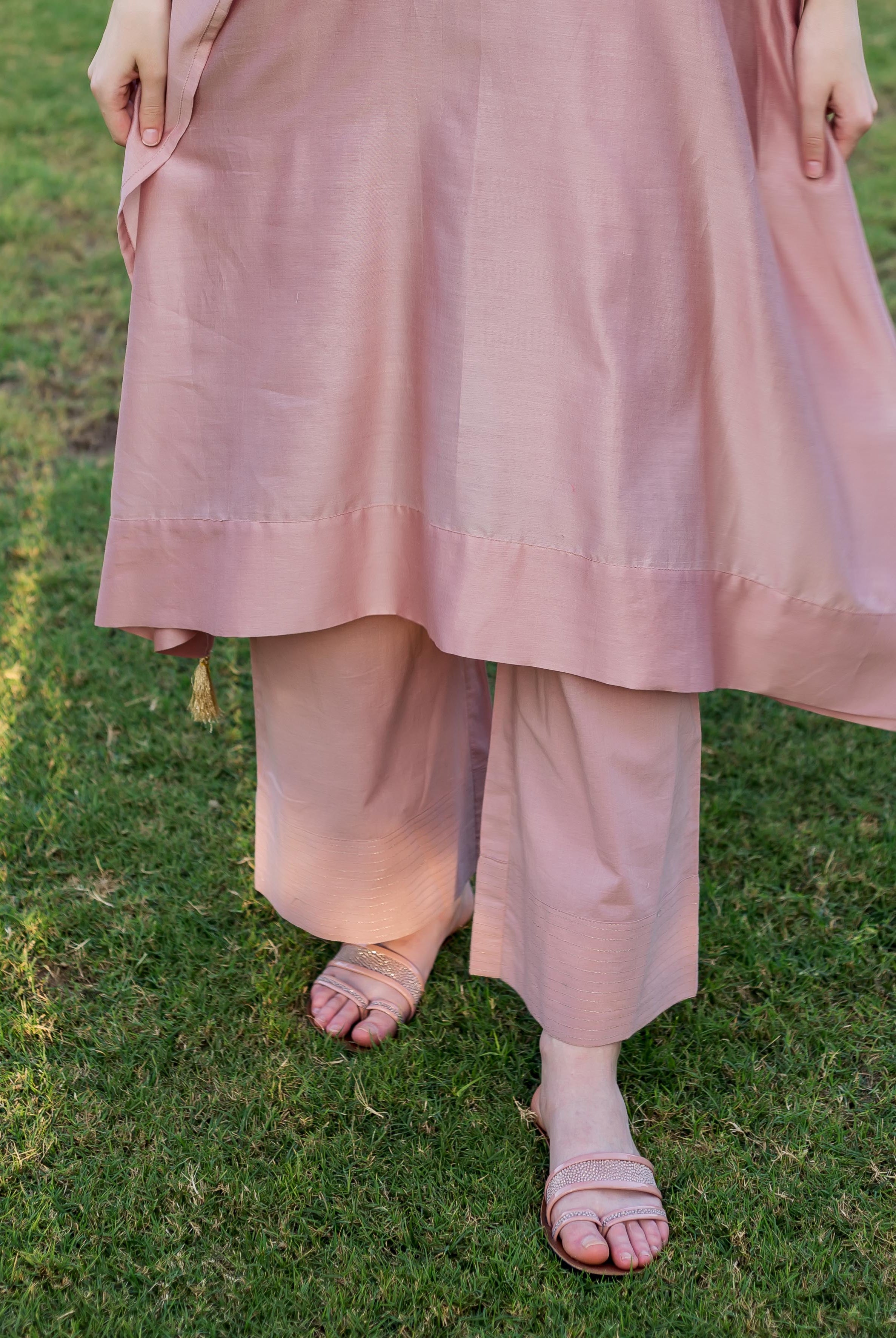 Model in dusty pink kaftan with tassels, matching palazzo pants and embellished sandals.