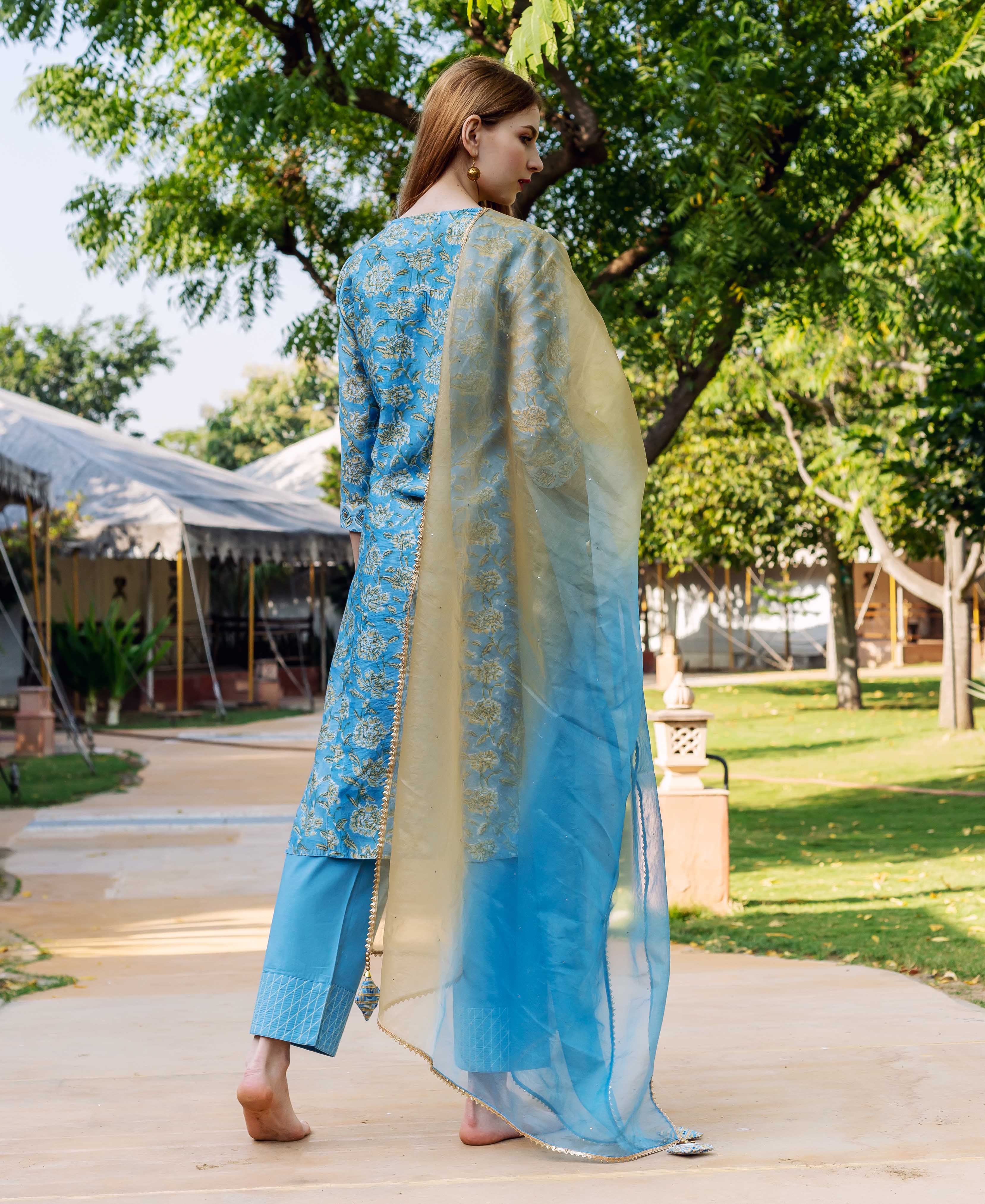 A model wearing a blue and gold floral print kurta with a sheer blue dupatta.
