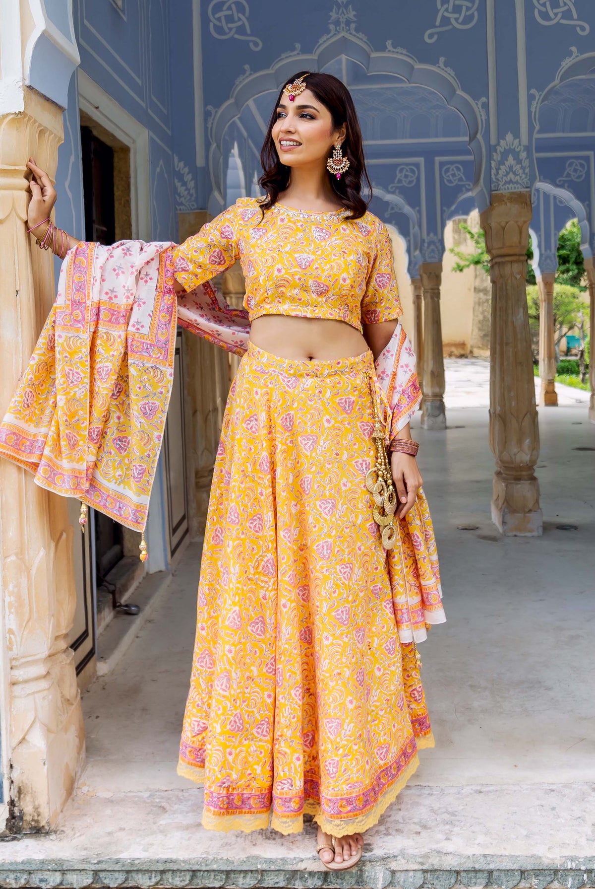Front full look of a model wearing a yellow and pink hand block printed lehenga set.