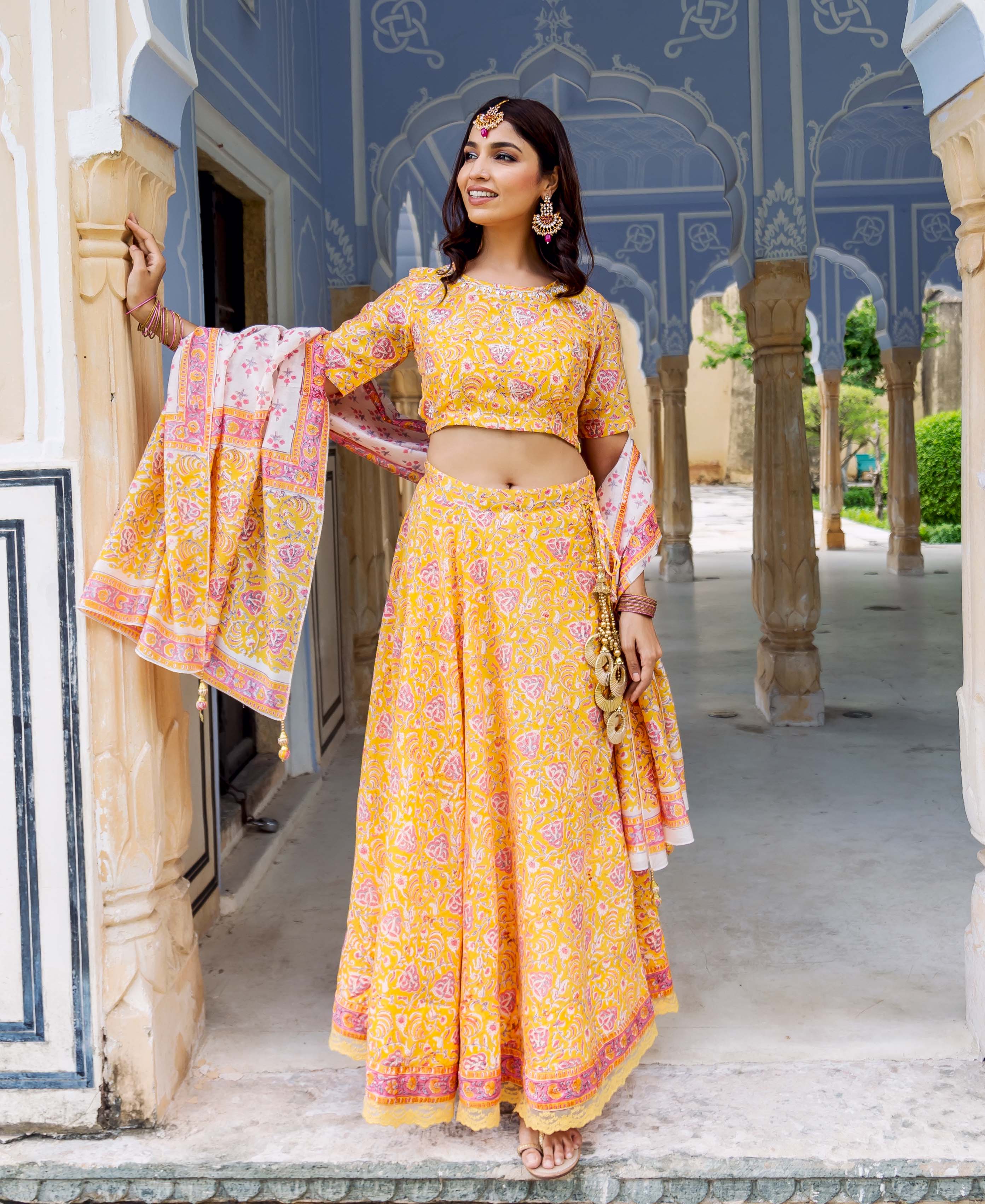 Front full look of a model wearing a yellow and pink hand block printed lehenga set.