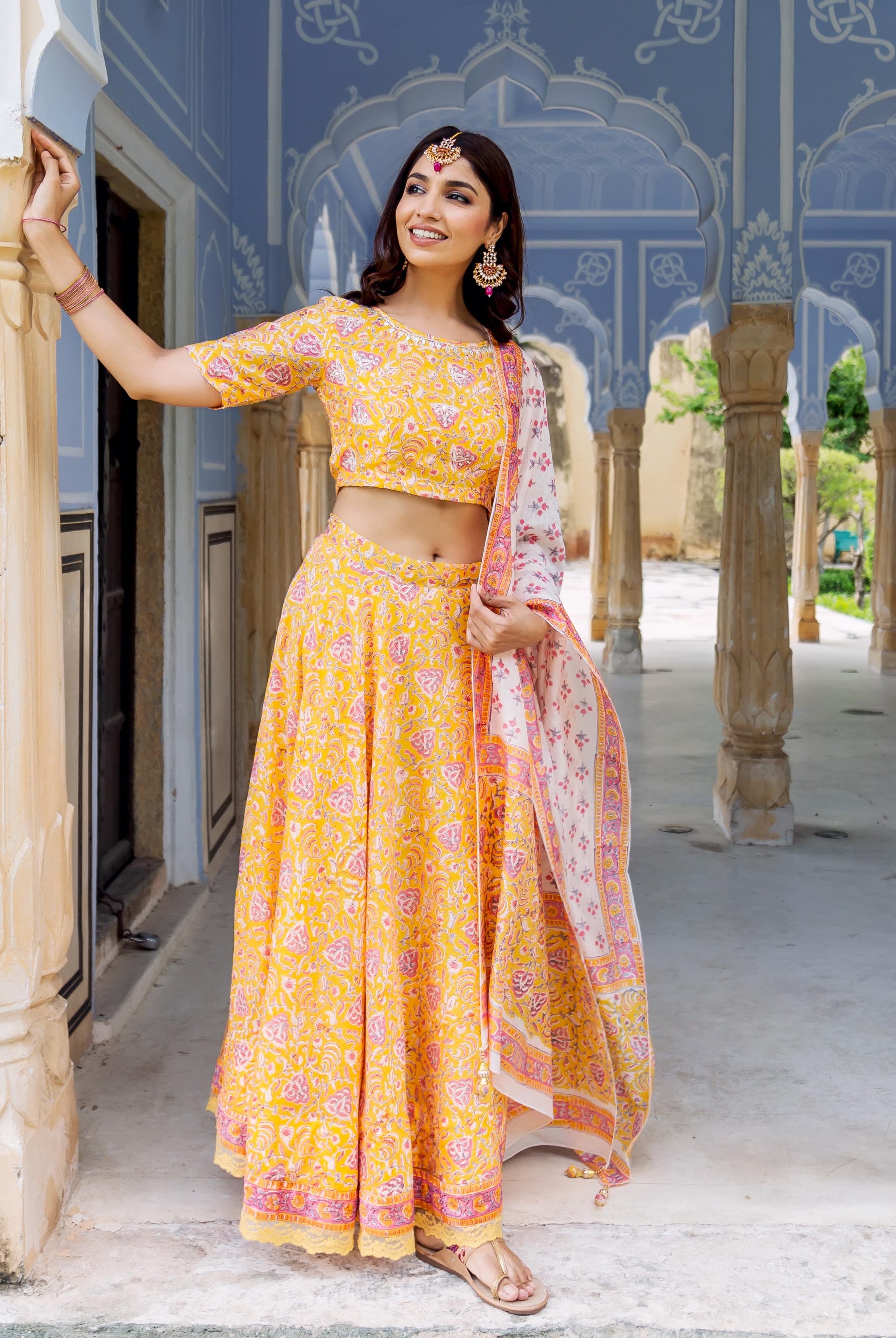 Model wears yellow hand-block printed lehenga set with a white patterned dupatta.