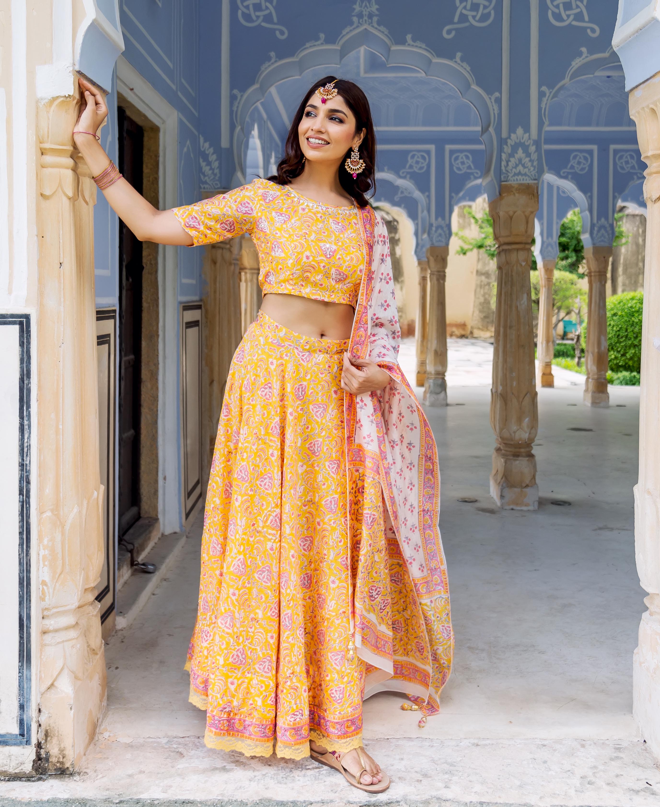 Model wears yellow hand-block printed lehenga set with a white patterned dupatta.