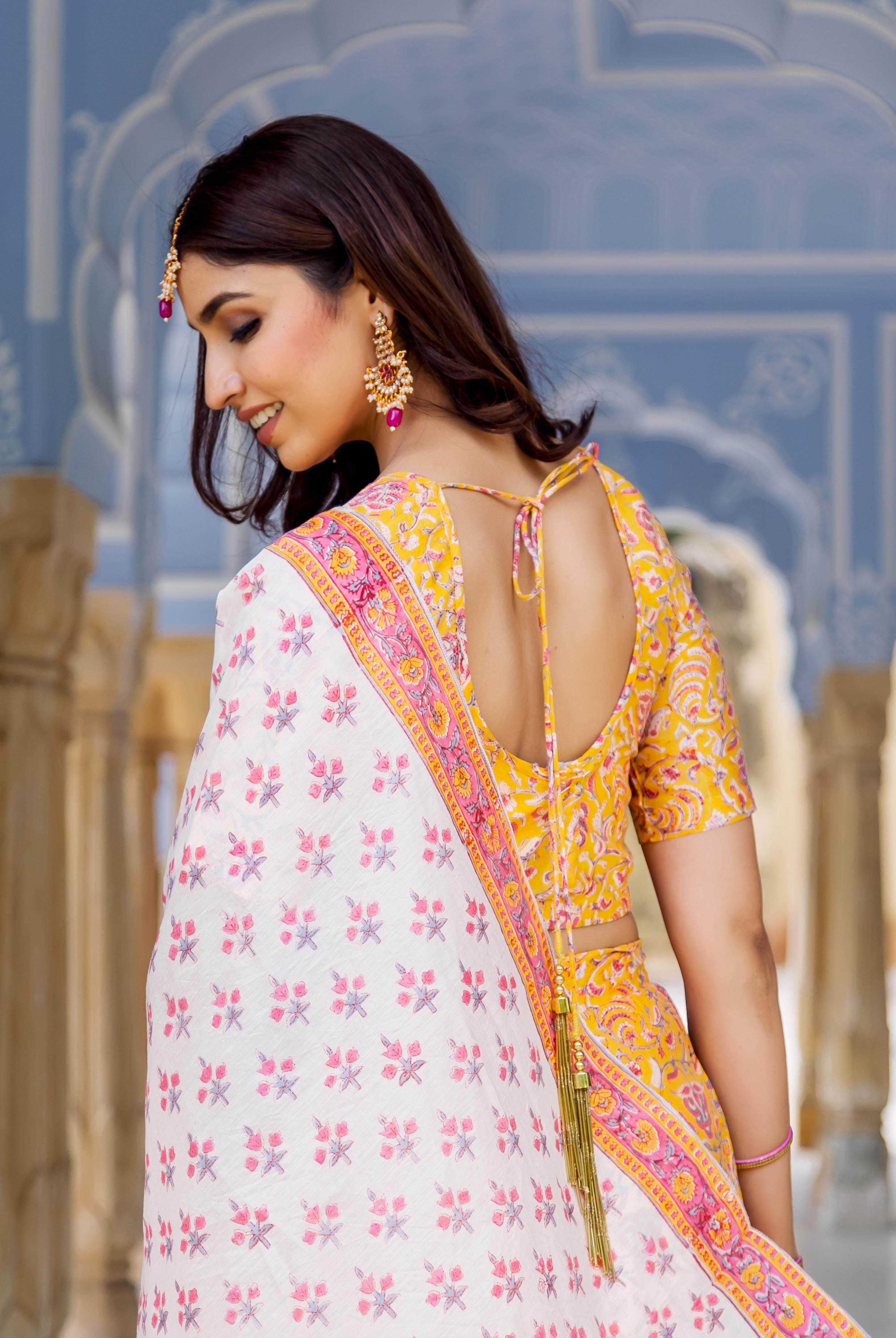 Side-back view of model in yellow and white hand block printed lehenga set.