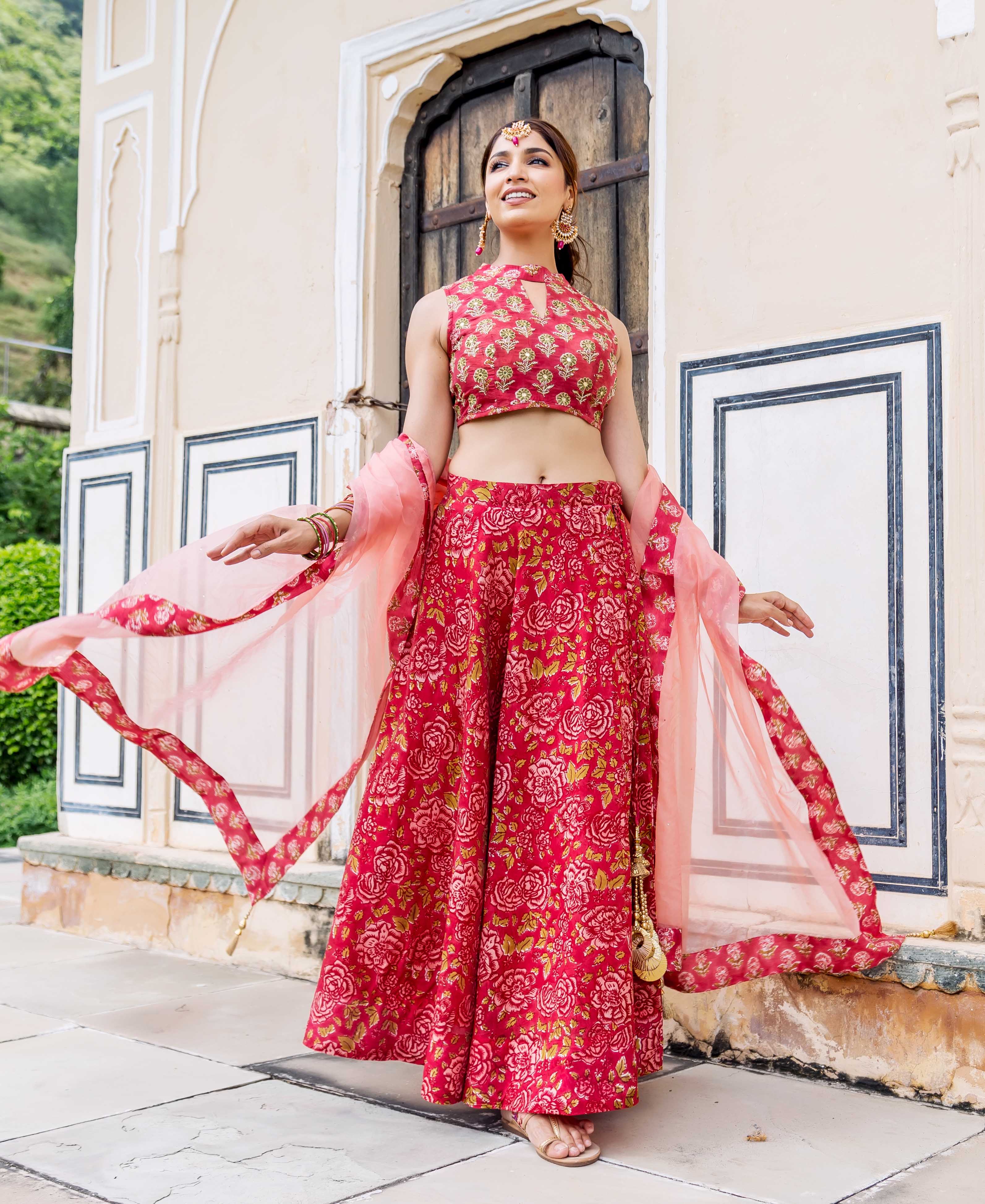 Smiling model in red hand block printed floral lehenga set with flowing dupatta.