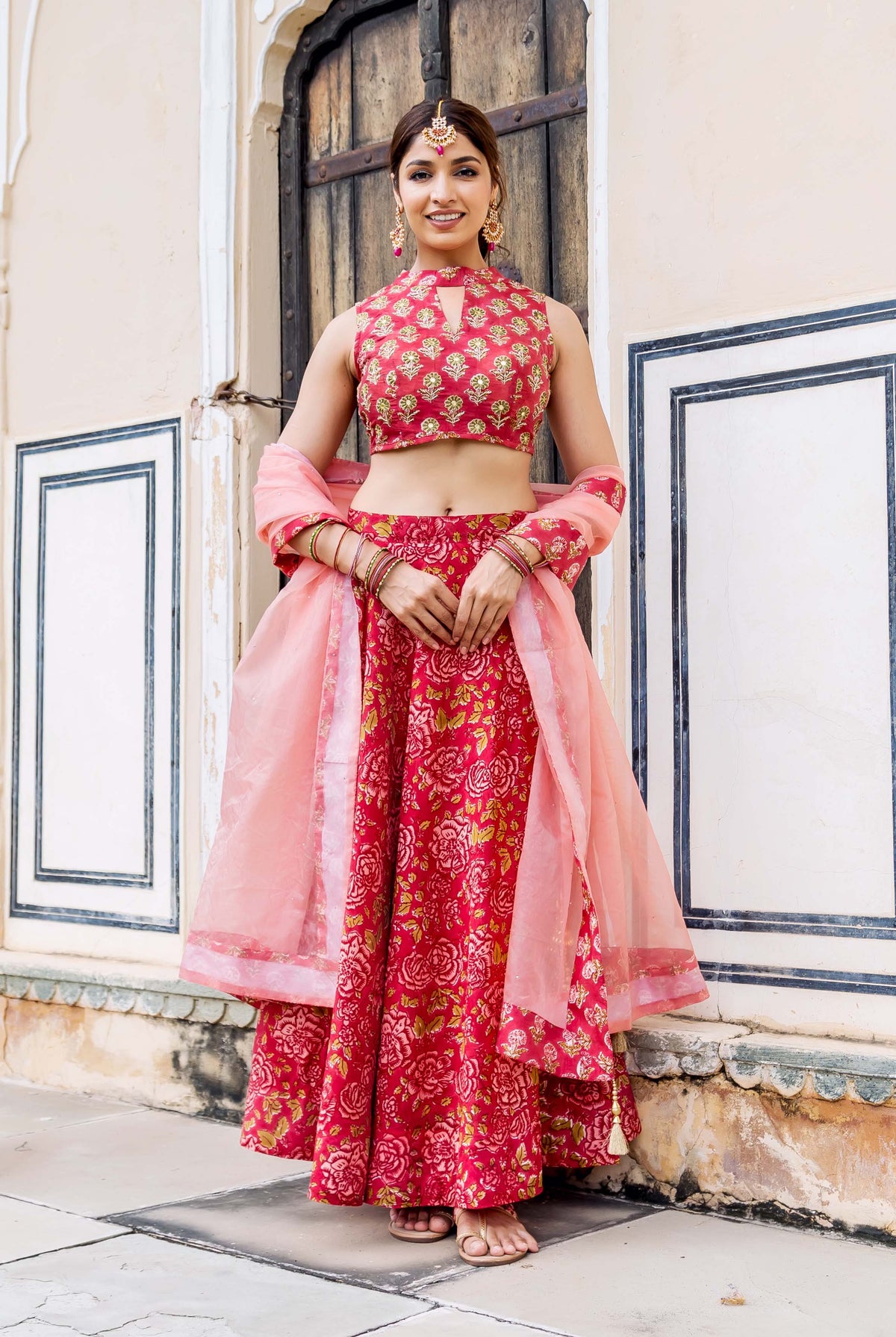 Model in vibrant red hand block printed floral and embroidered lehenga set.