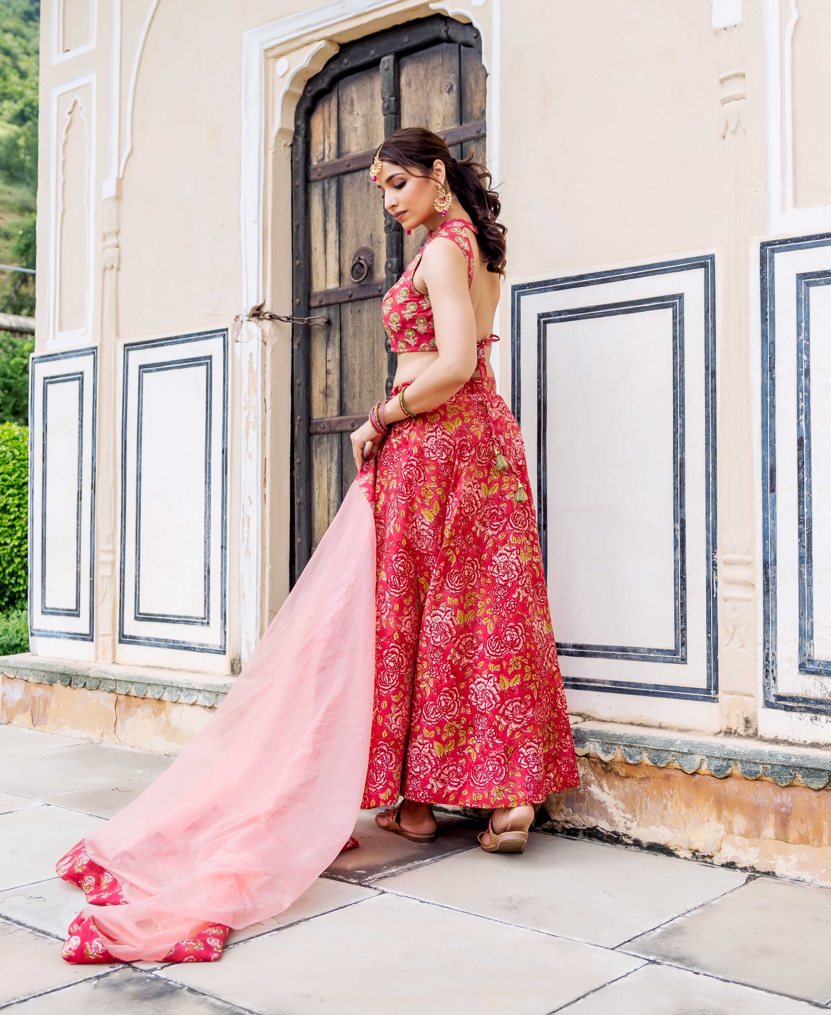 Woman in red hand-block printed floral lehenga set with a light pink dupatta.
