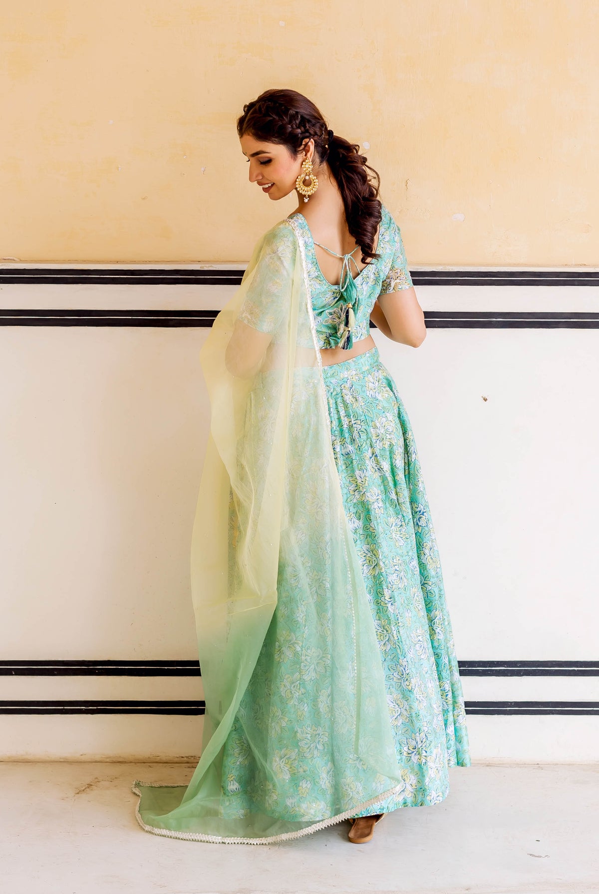 A model wearing a green floral lehenga set with a sheer dupatta.