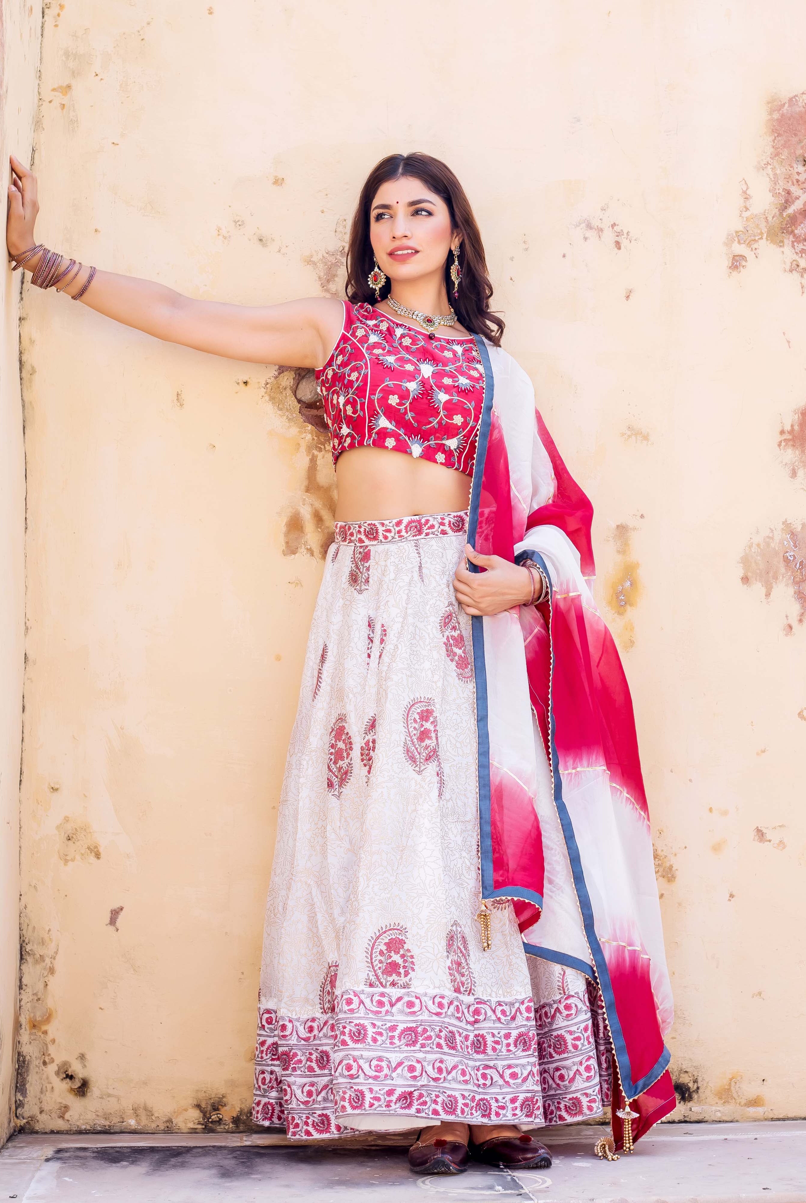 Full shot of model in red embroidered blouse and white hand-block printed lehenga set.