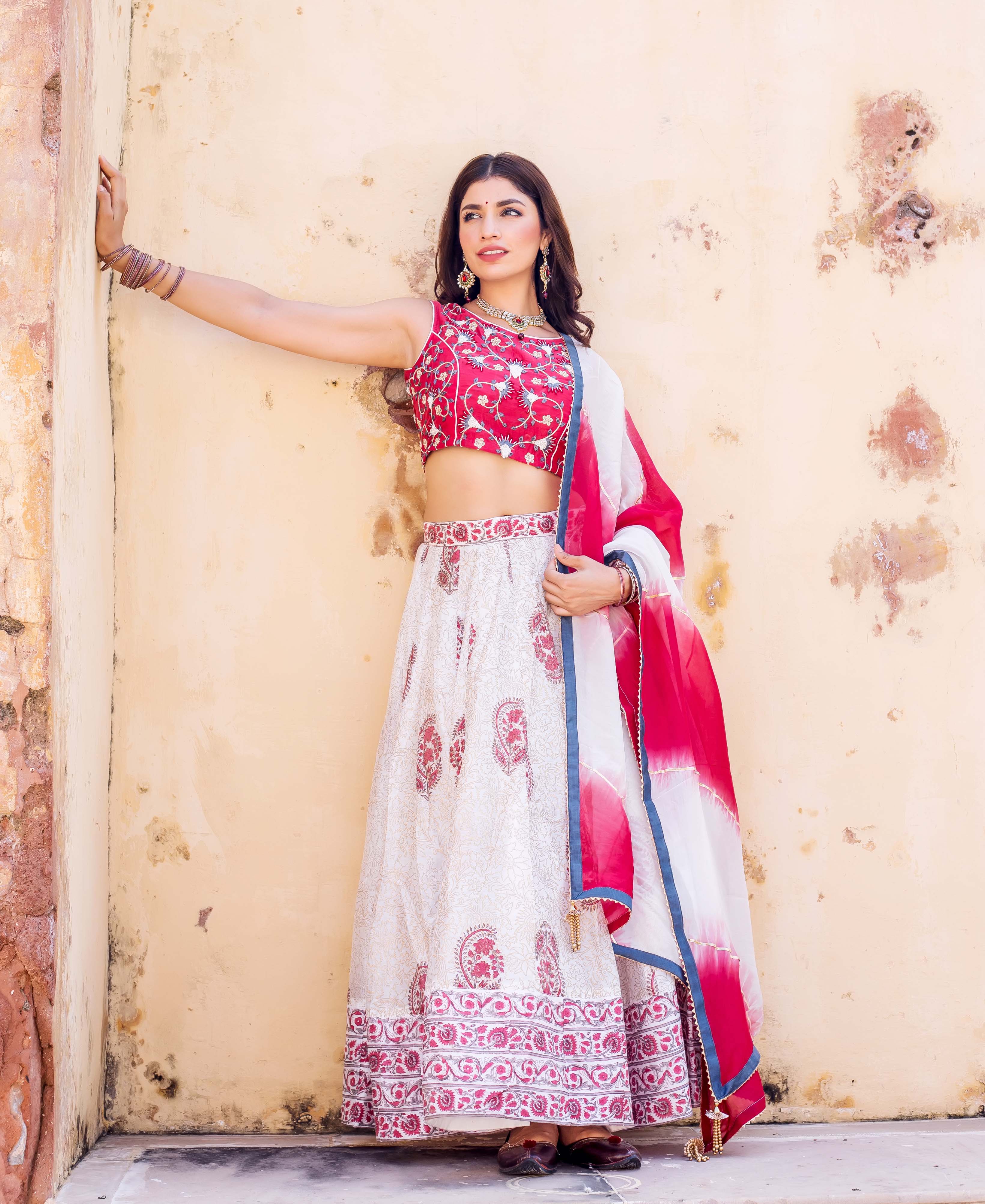 Full shot of model in red embroidered blouse and white hand-block printed lehenga set.