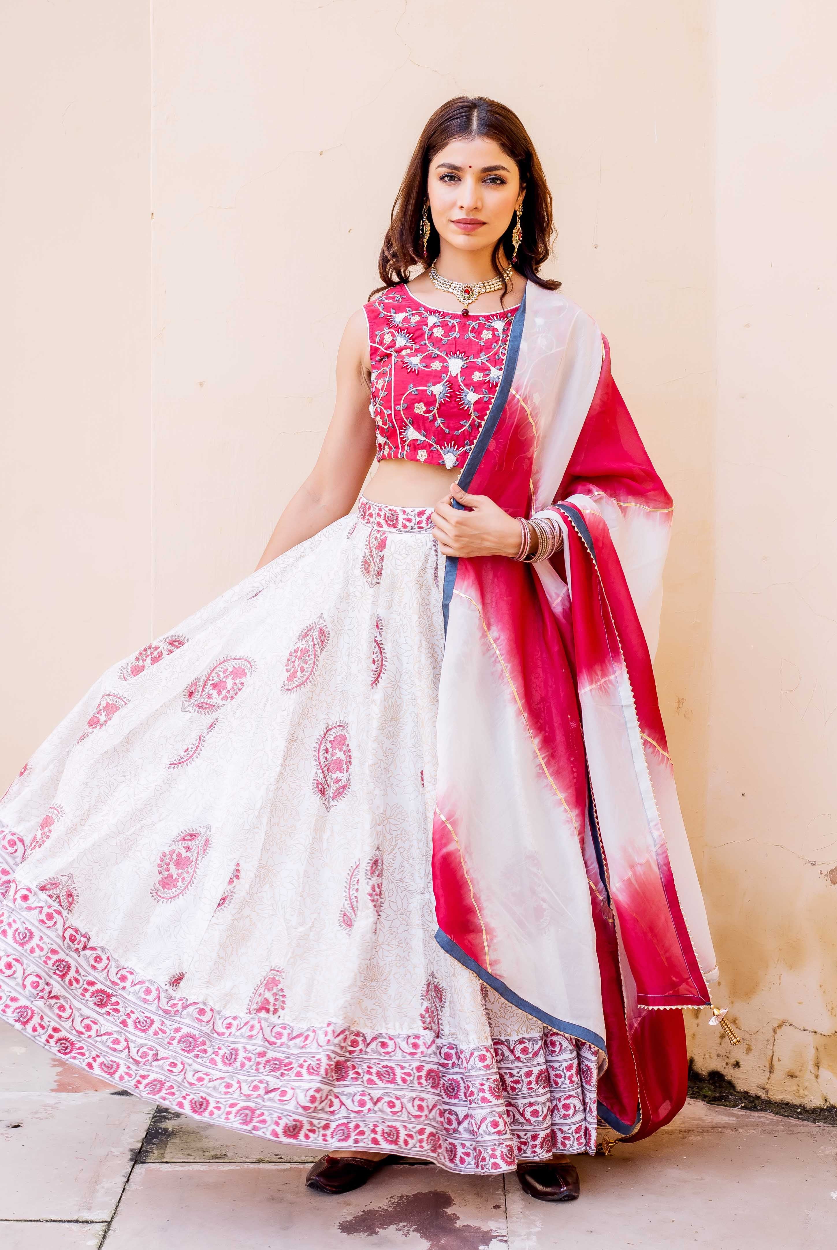 Model in white, red hand-block printed lehenga set, embroidered choli, and tie-dye dupatta.