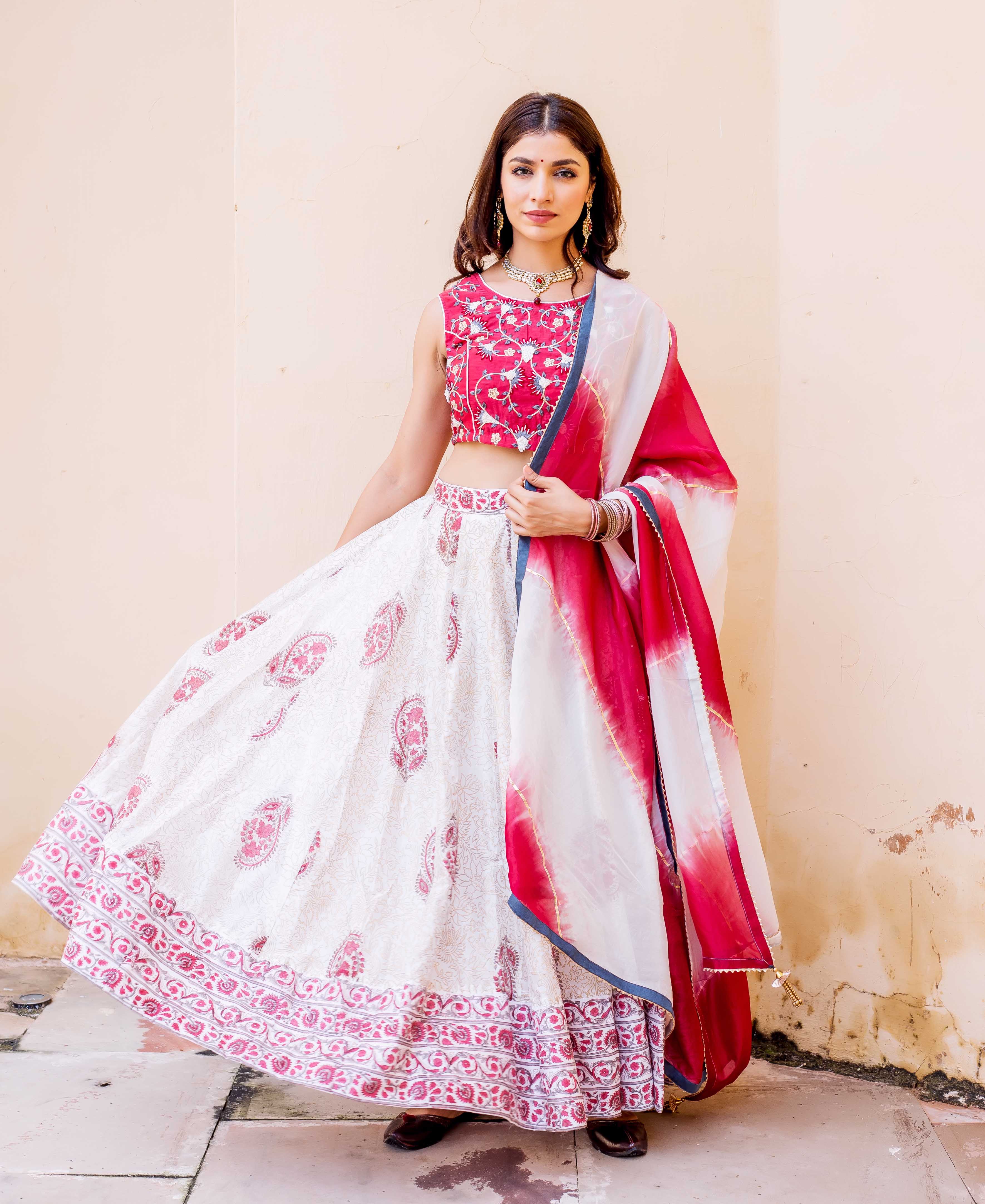 Model in white, red hand-block printed lehenga set, embroidered choli, and tie-dye dupatta.