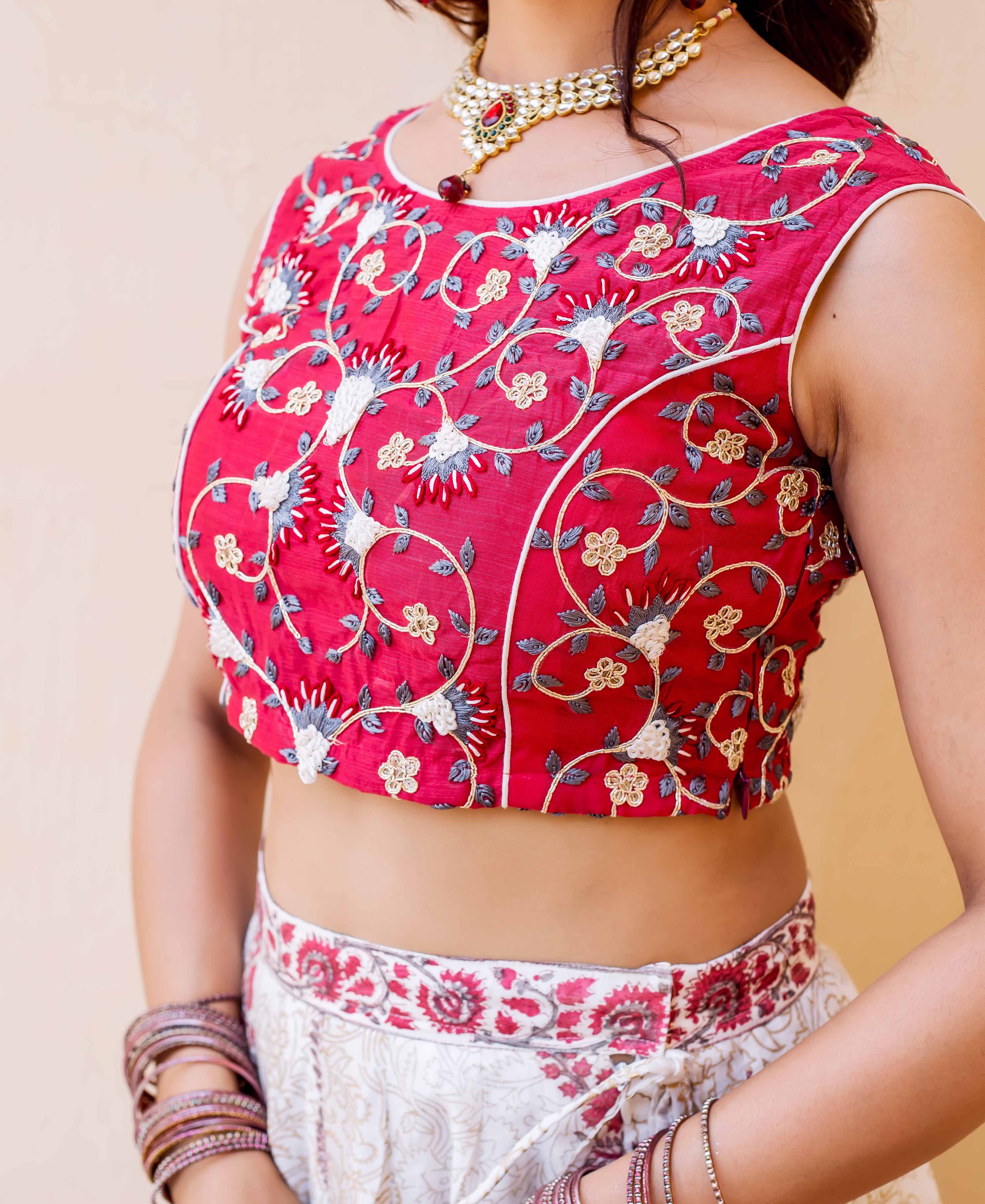 Model in a red embroidered blouse and white hand-block printed lehenga skirt.