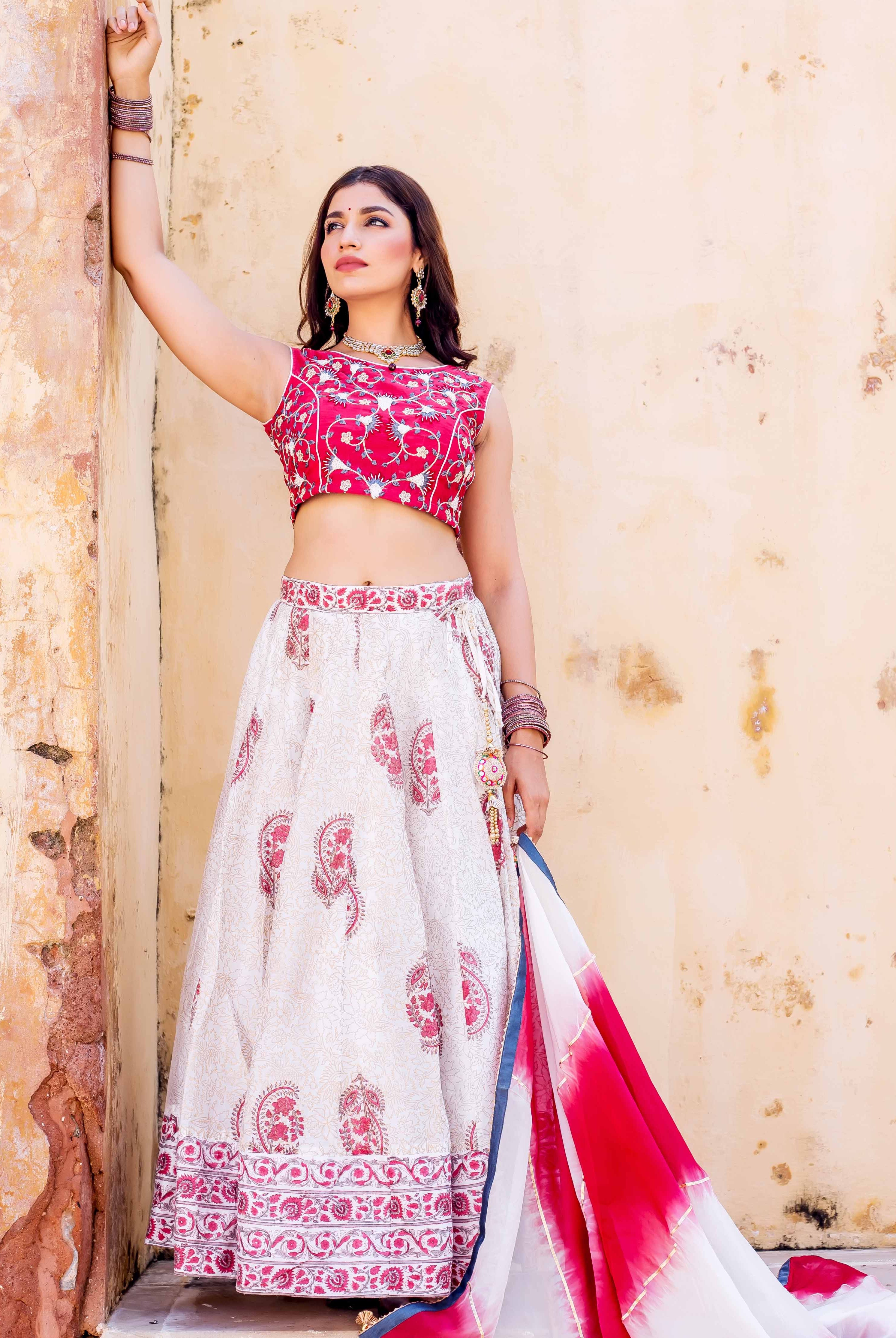 Model in red embroidered crop top and white hand-block printed lehenga set.