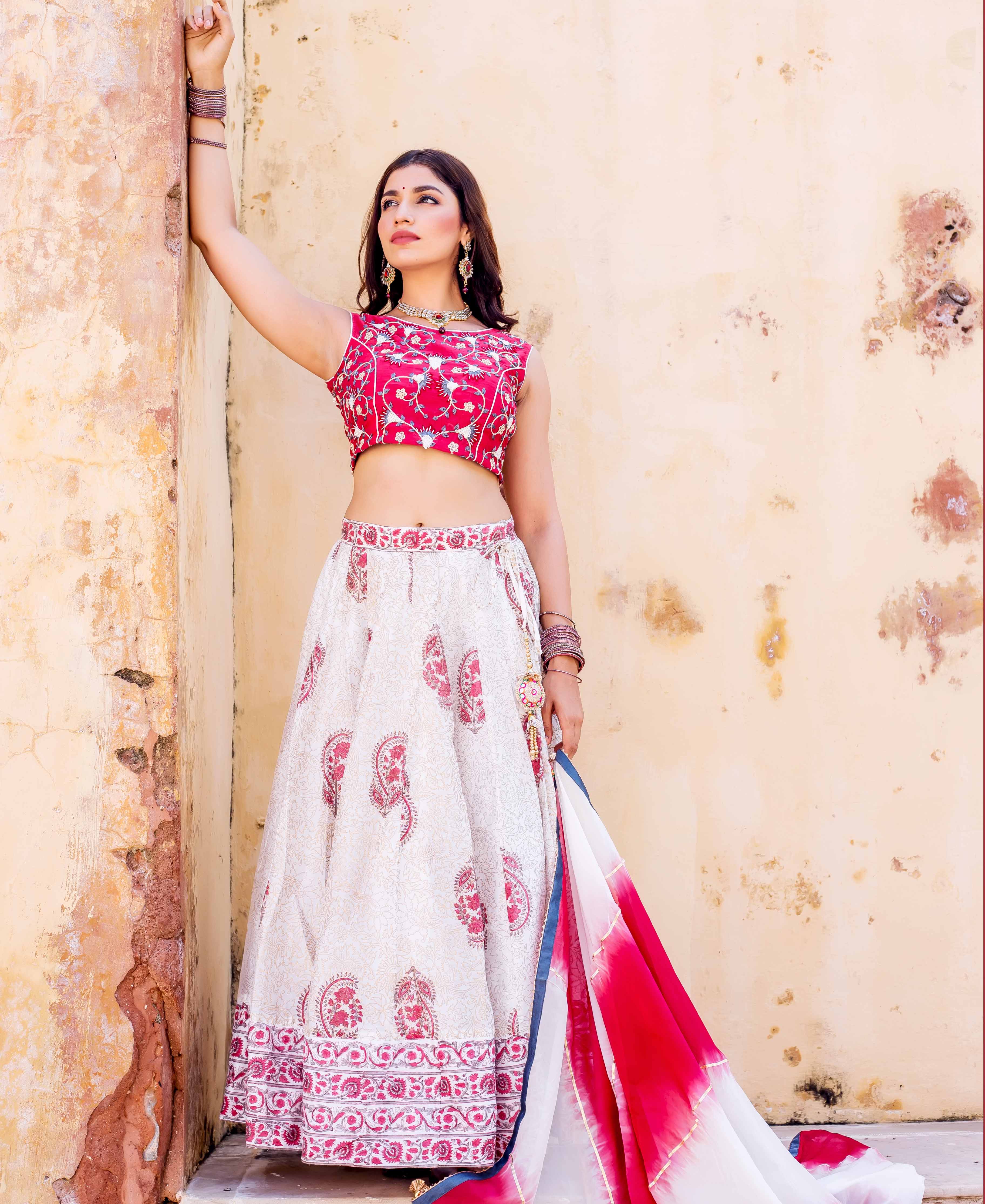 Model in red embroidered crop top and white hand-block printed lehenga set.