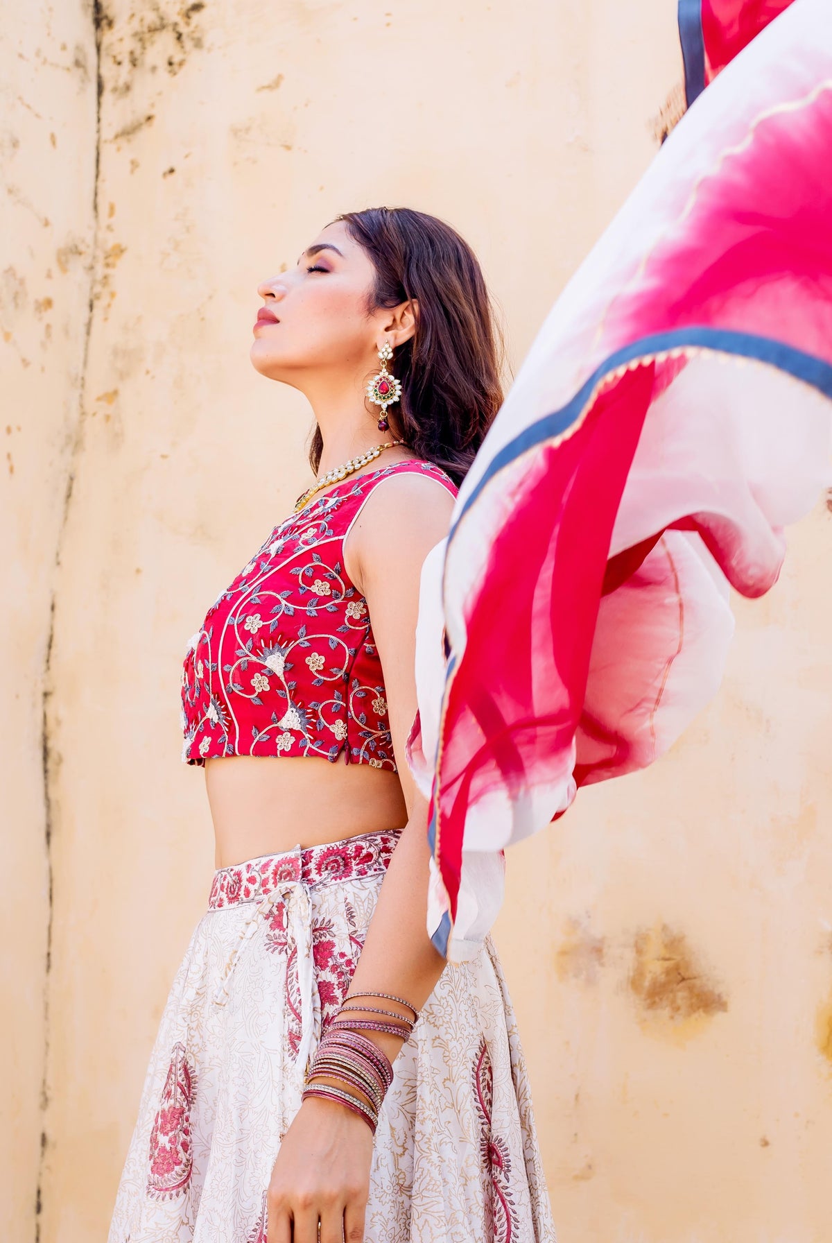 Model in red embroidered crop top and white hand-block printed lehenga set.