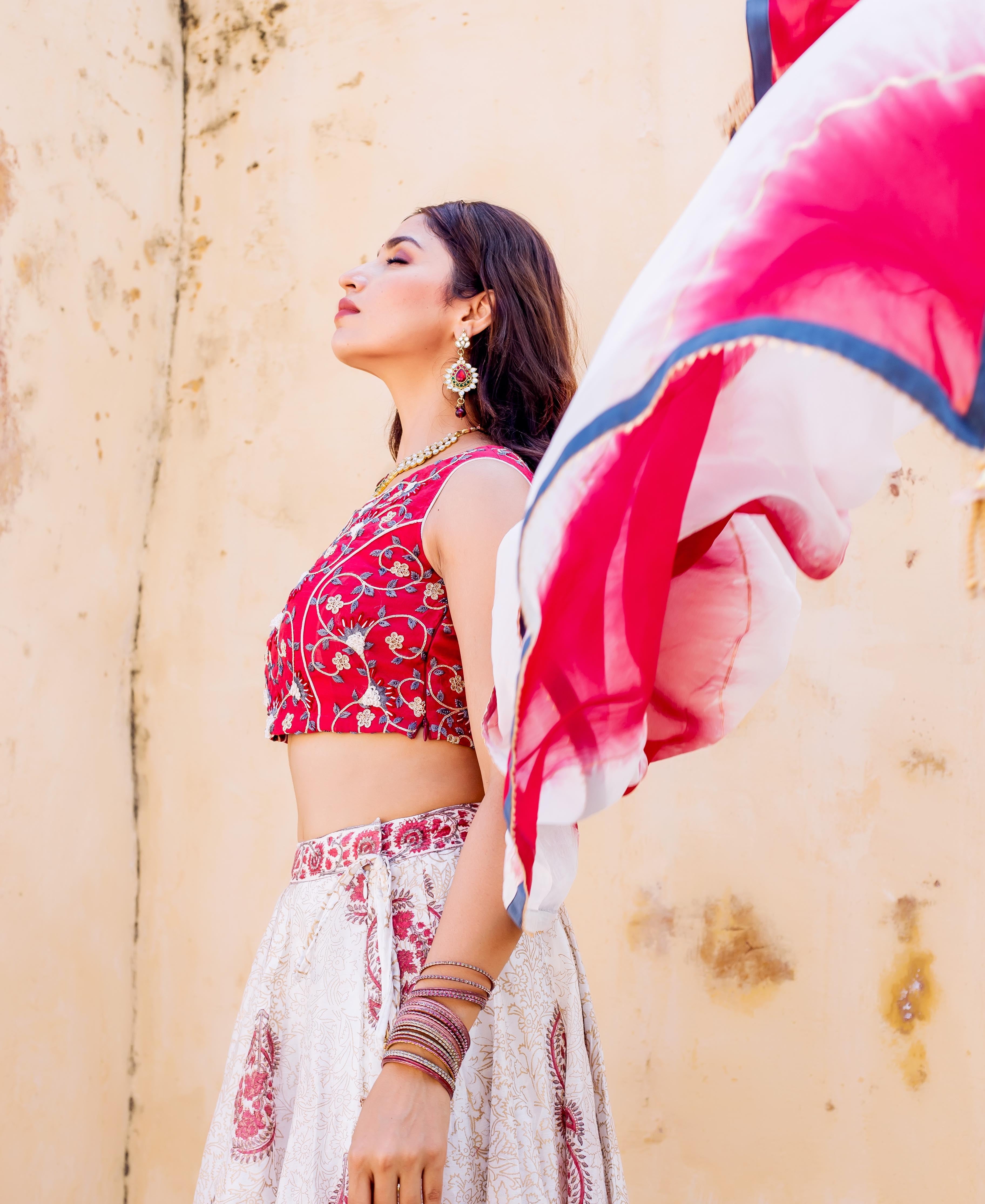 Model in red embroidered crop top and white hand-block printed lehenga set.