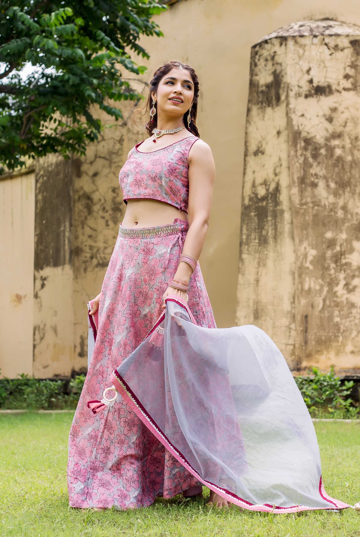 Model wearing Aayesha pink and grey floral hand block printed lehenga set, with dupatta.