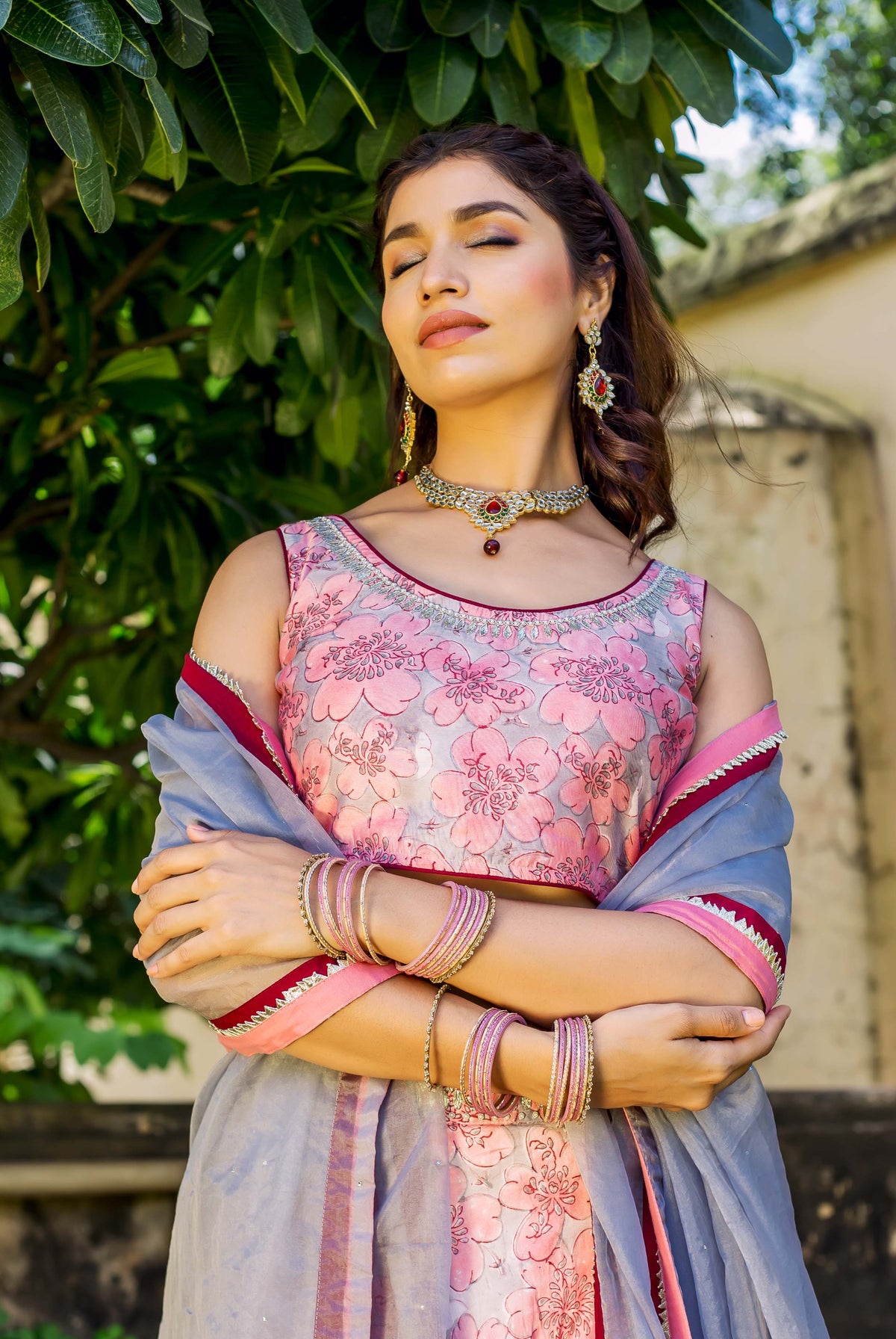 Woman in pink and grey hand block printed lehenga set with floral design and bangles.
