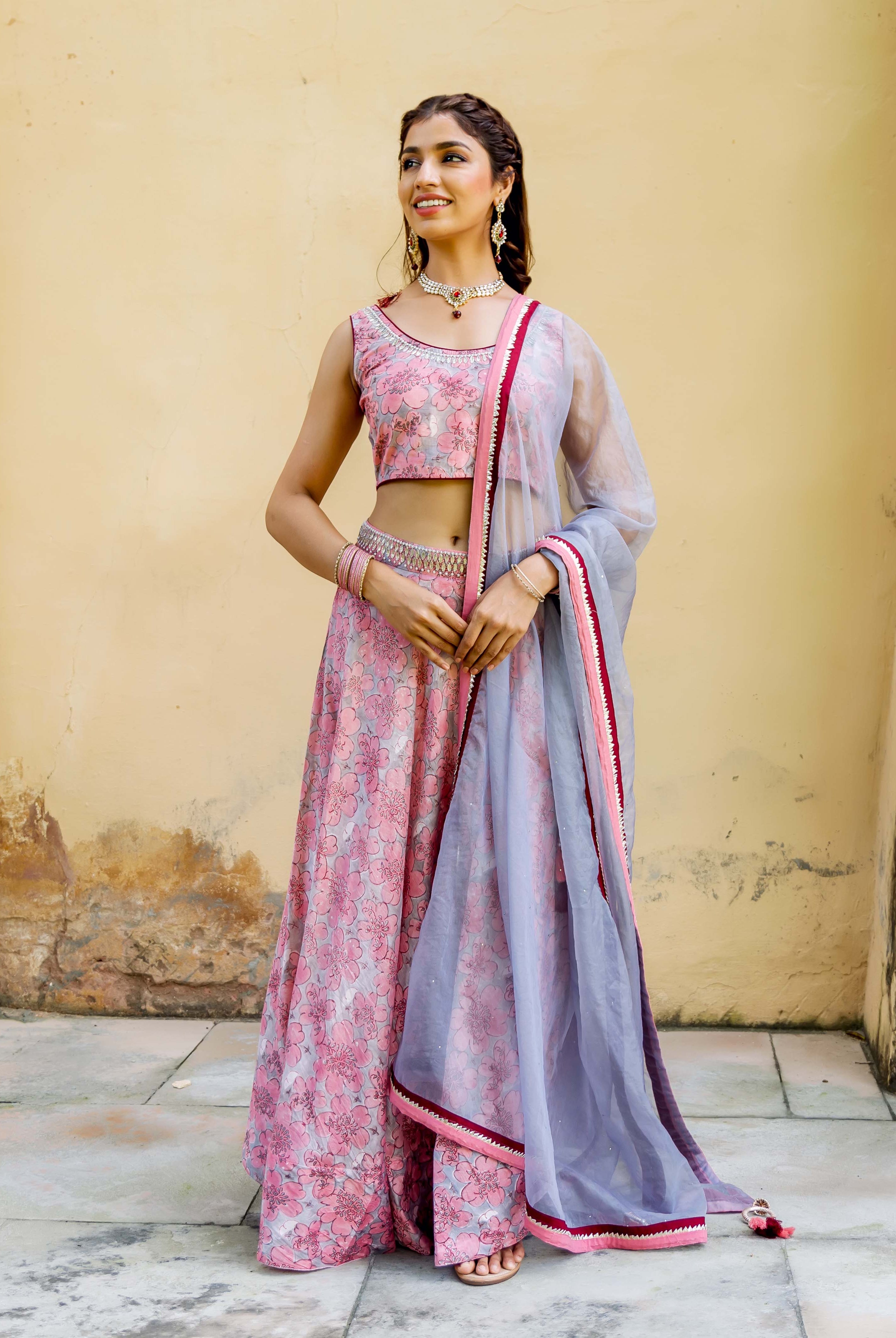 Front view of a model in a pink and grey hand block printed floral lehenga set.