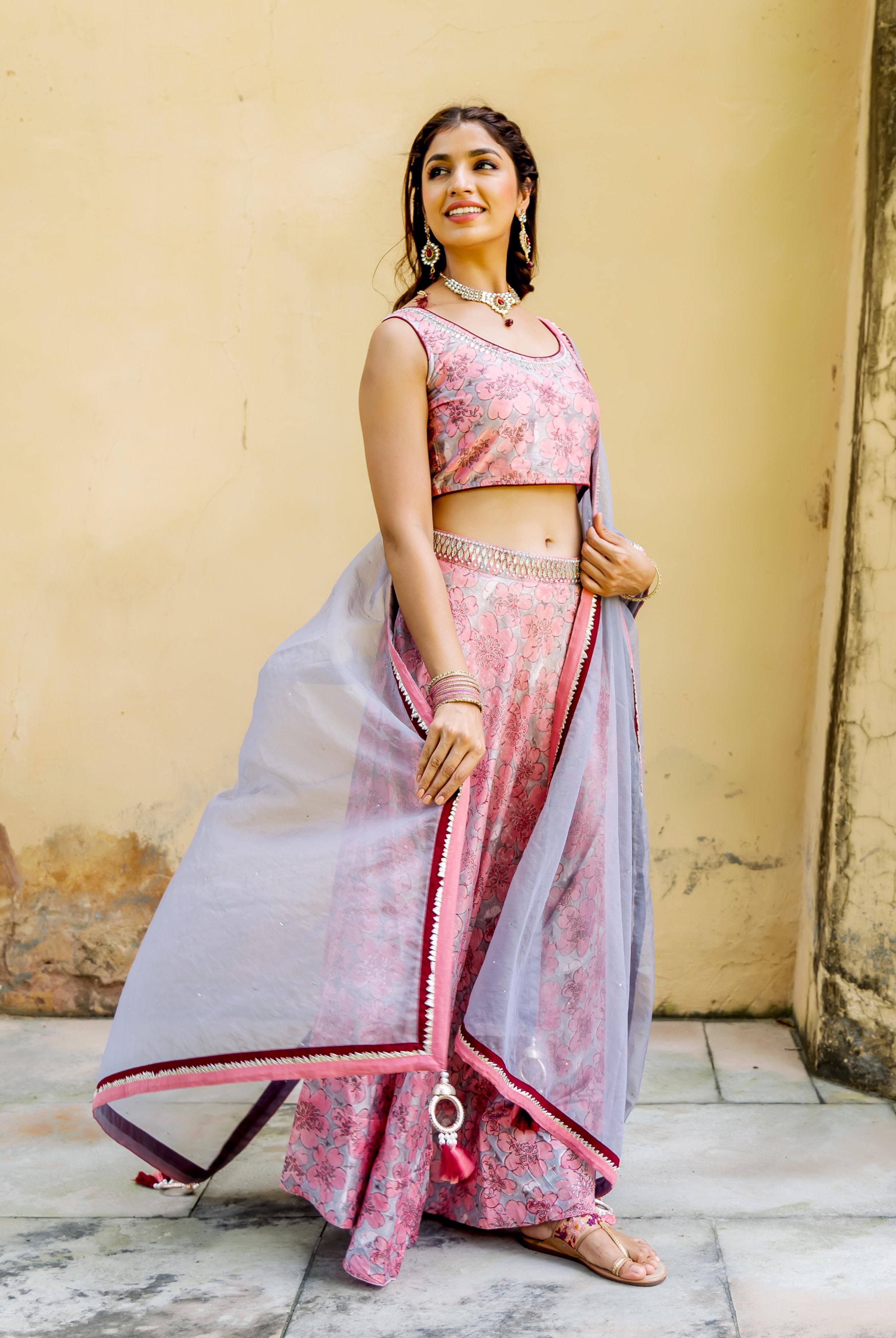 Full-length, side-facing model wears a pink and grey hand block printed lehenga set.