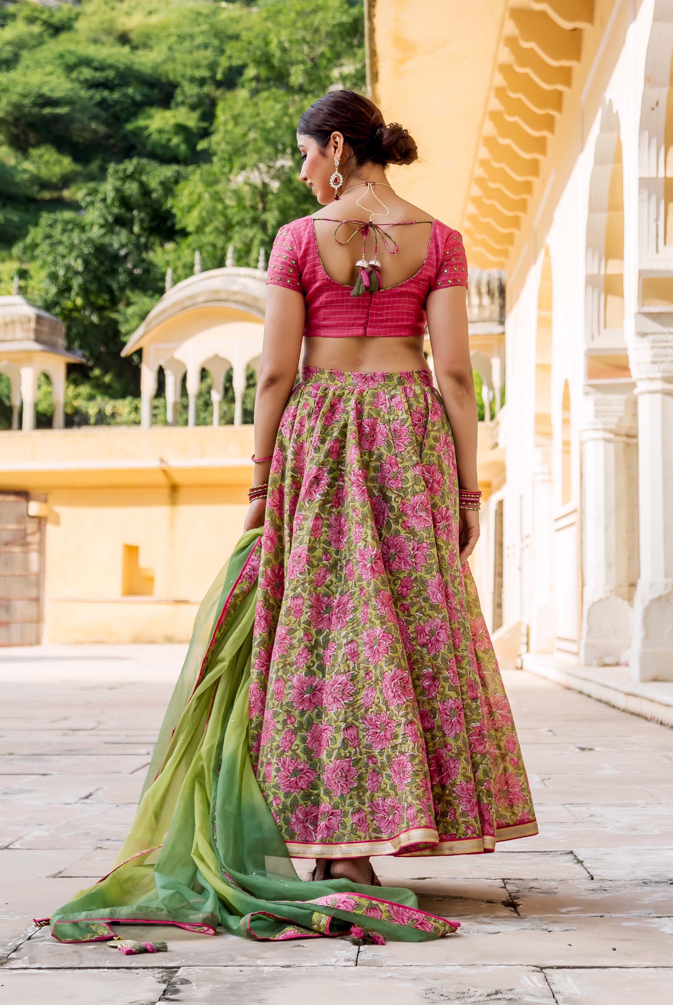 Model from back in pink blouse, green floral hand block printed lehenga, and green dupatta.