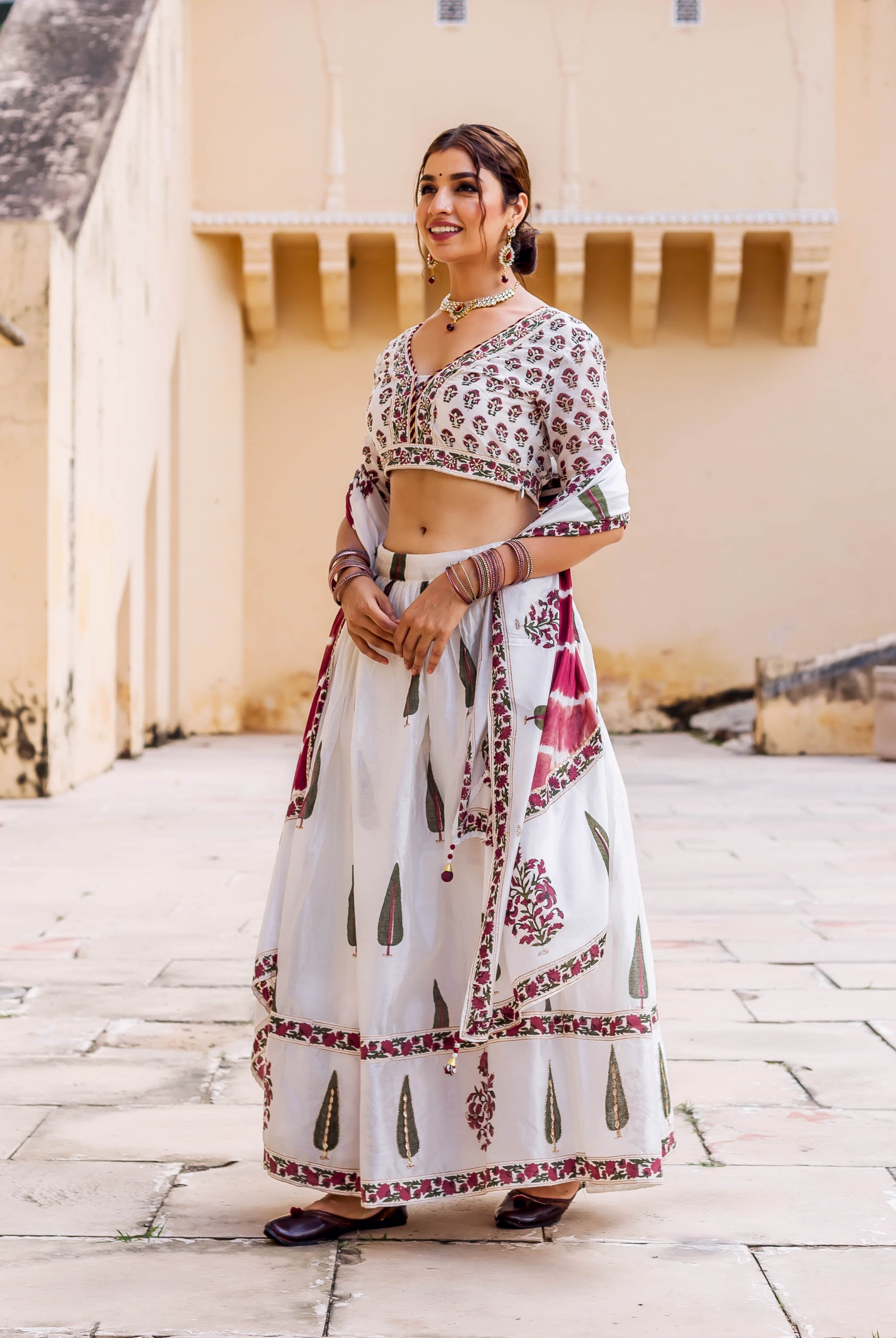 Model in white hand-block printed lehenga set with maroon, green, and embroidered details.