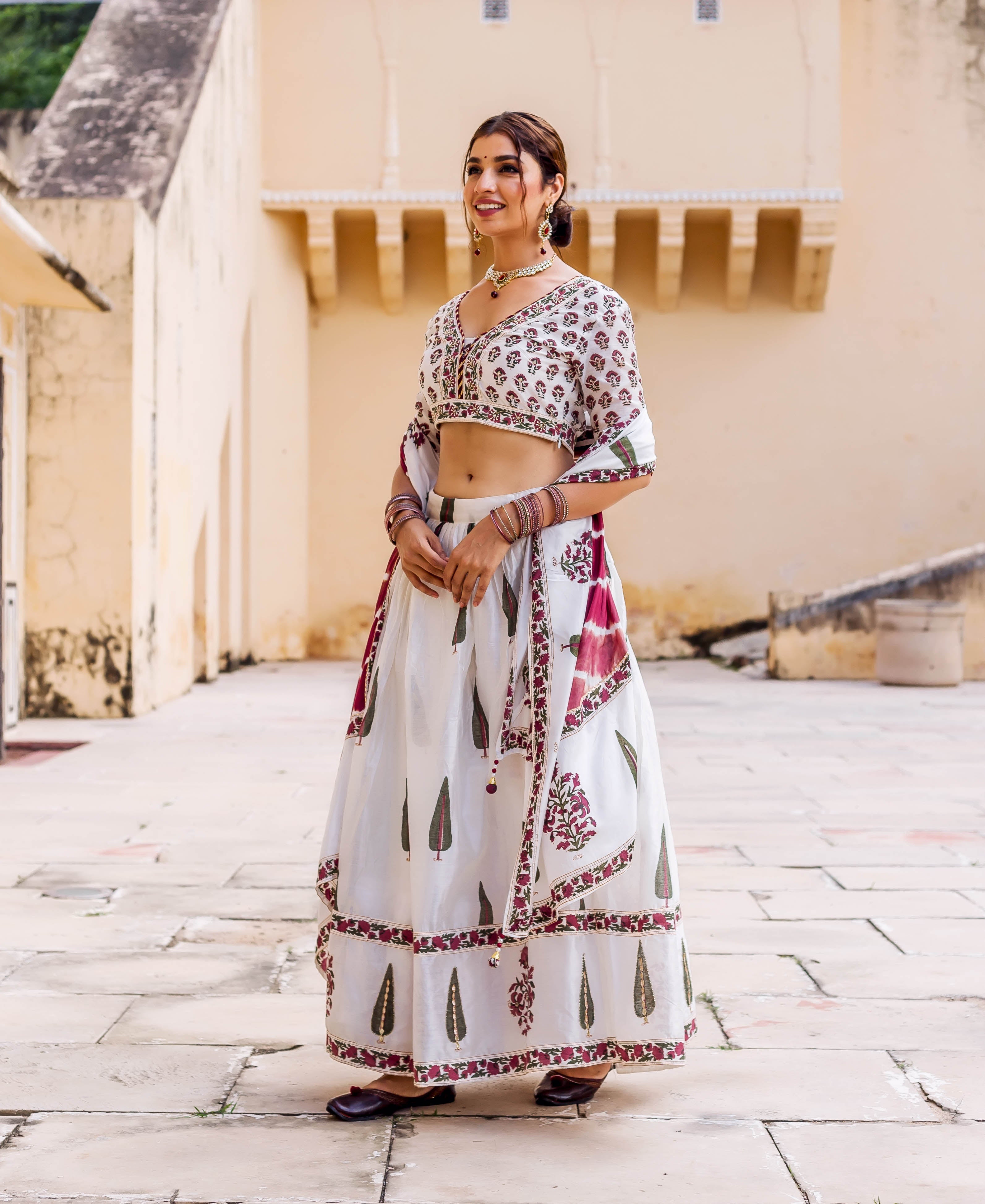 Model in white hand-block printed lehenga set with maroon, green, and embroidered details.
