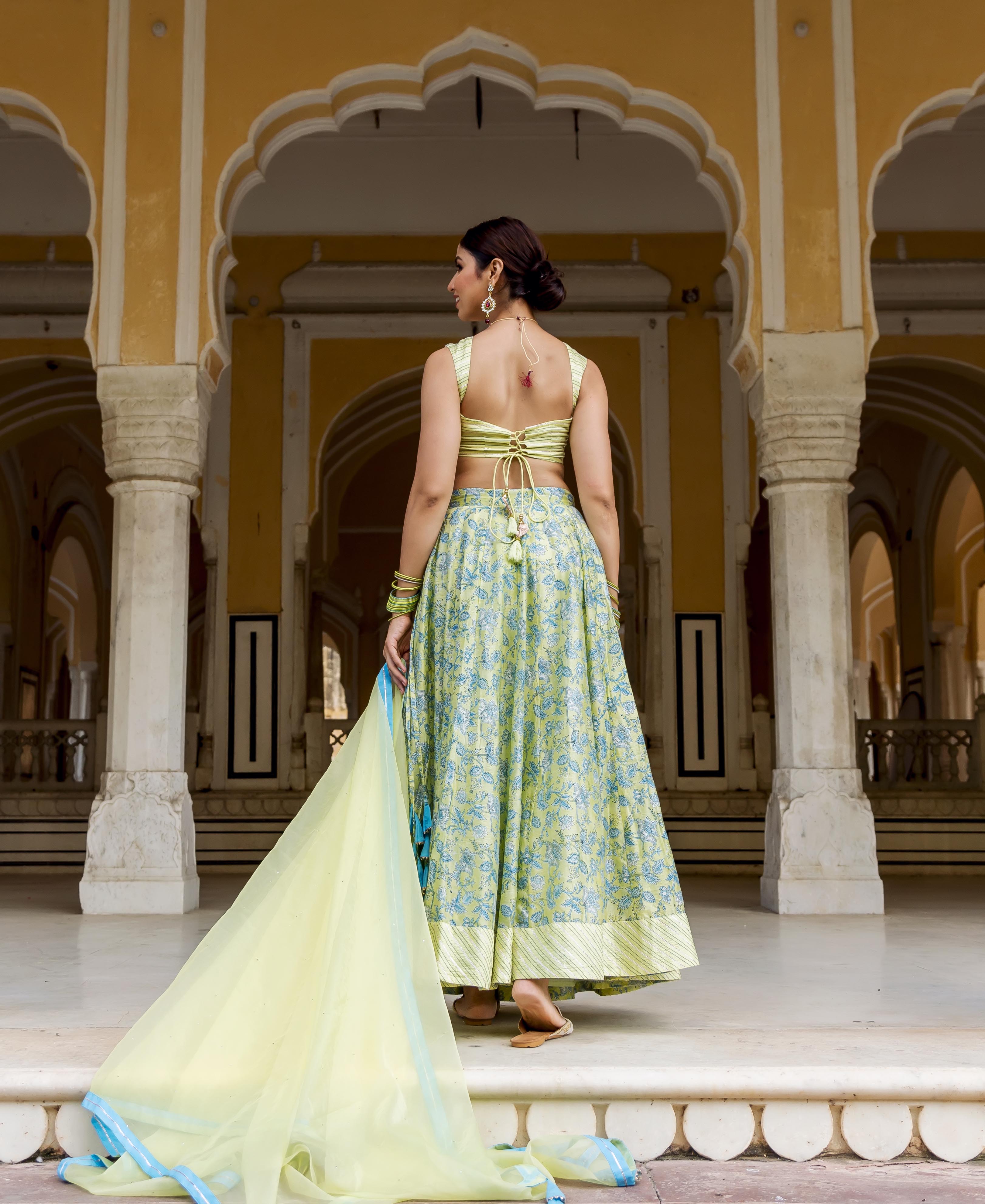 Back view of model in light green, blue hand-block printed lehenga set with tie-up choli.