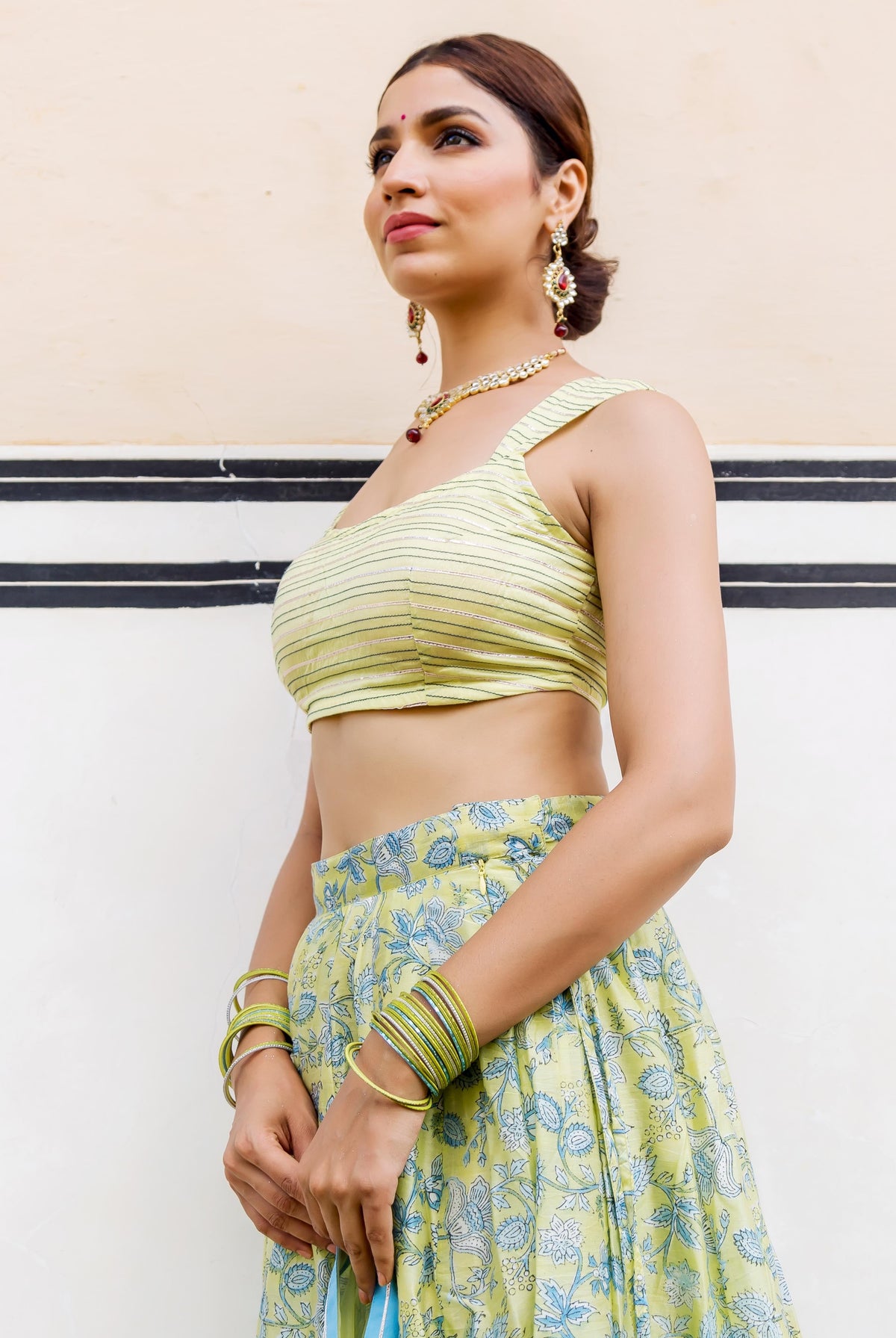 Side view of model in lime green striped crop top and floral hand-block printed lehenga.