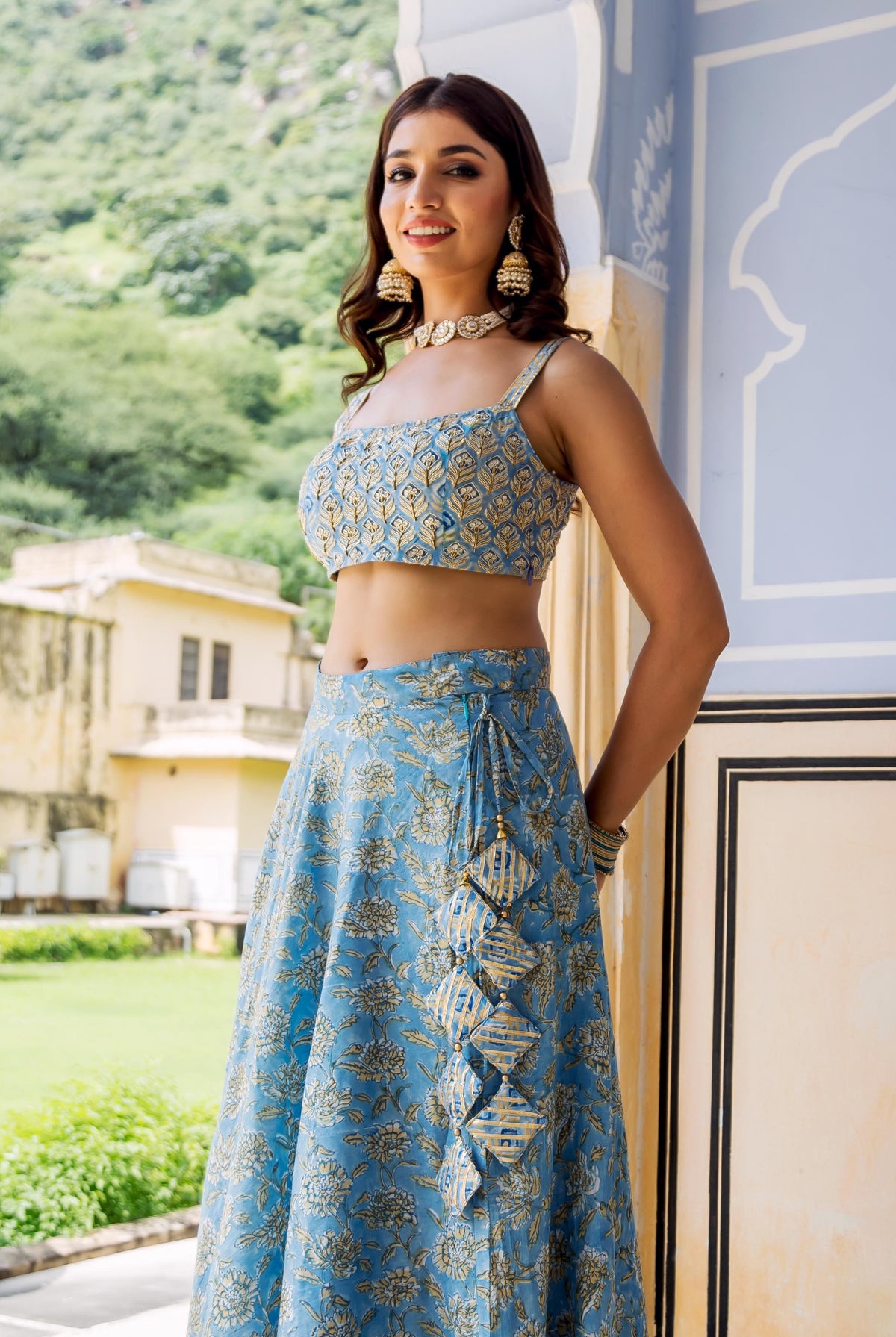 Front view of model in light blue hand-block printed lehenga set with gold floral patterns.