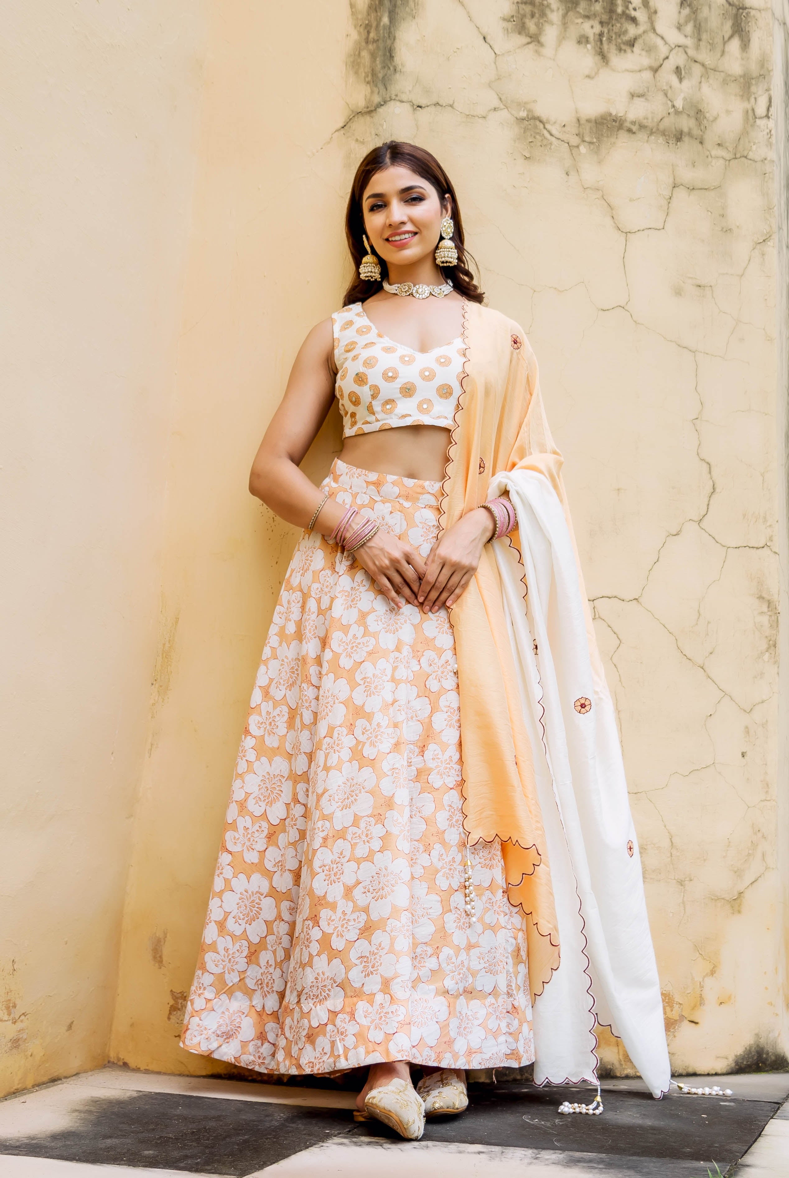 Model in a full-length off-white and peach block printed and embroidered lehenga set.