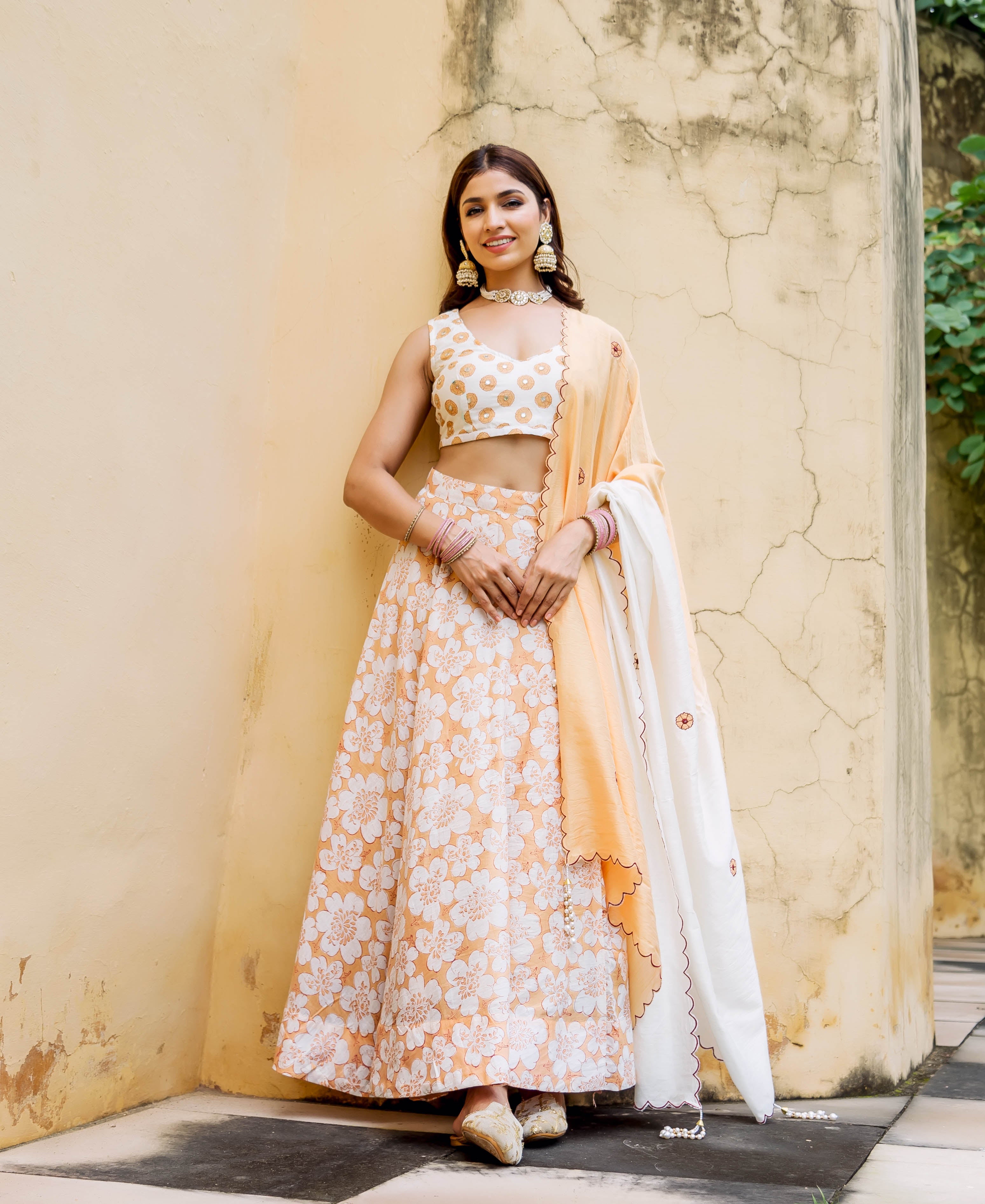 Model in a full-length off-white and peach block printed and embroidered lehenga set.