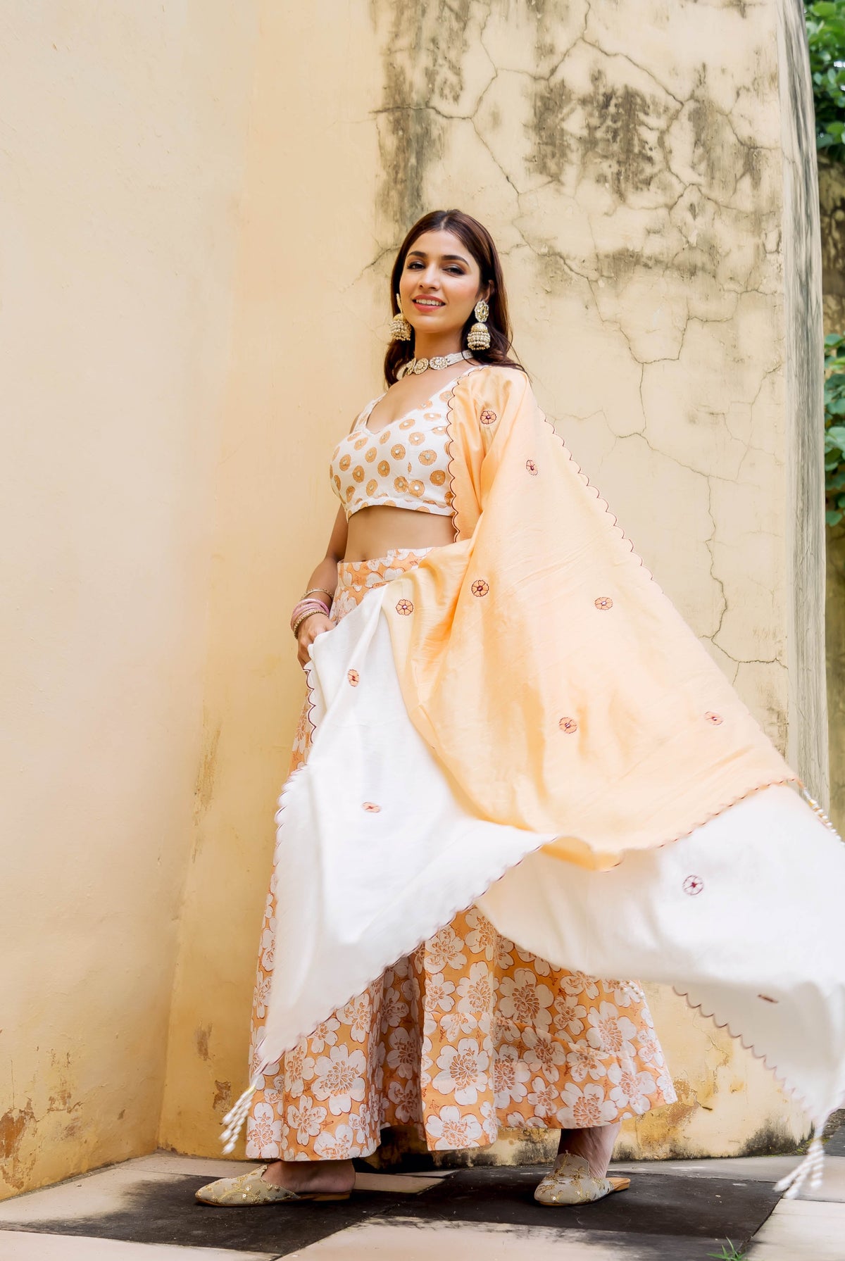 Model in an off-white and peach block printed and embroidered lehenga set.