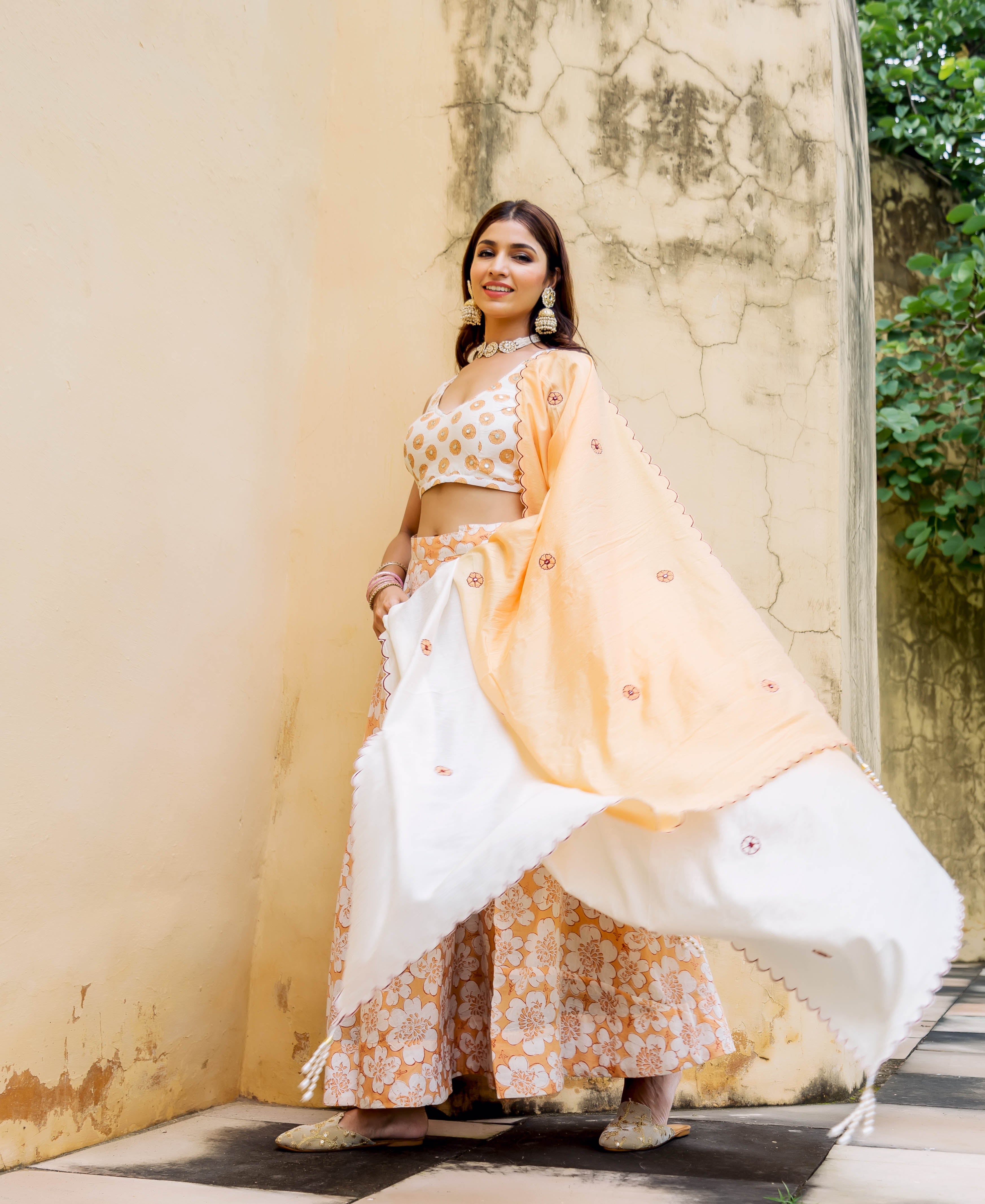 Model in an off-white and peach block printed and embroidered lehenga set.