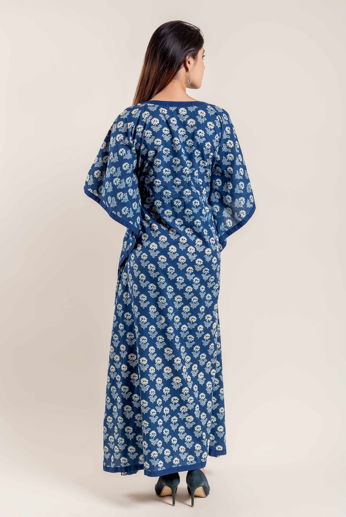 Indigo kaftan with white floral pattern, on model from behind, dark shoes.