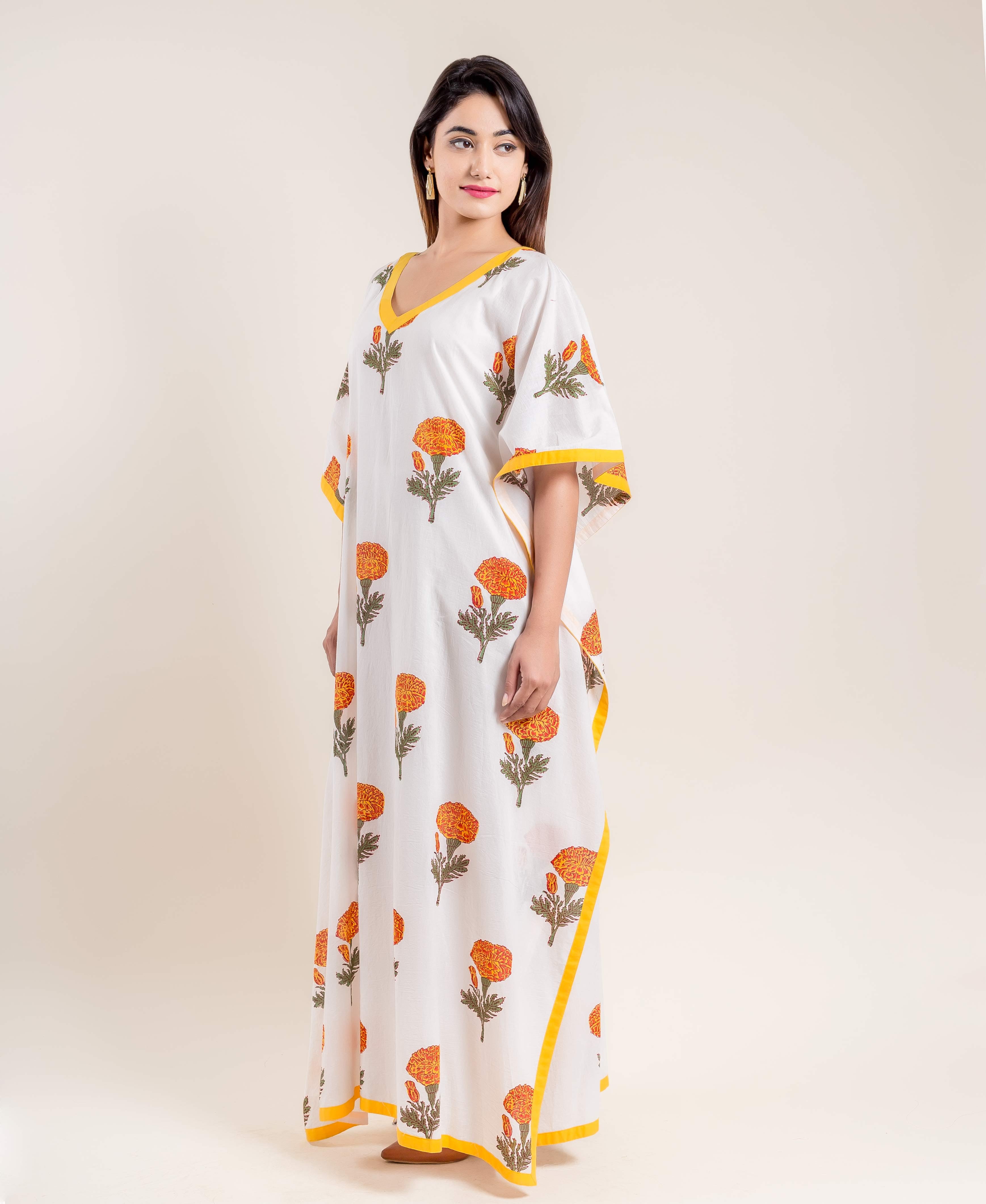 Model wearing white hand block printed V-neck kaftan with marigold print and yellow trim.
