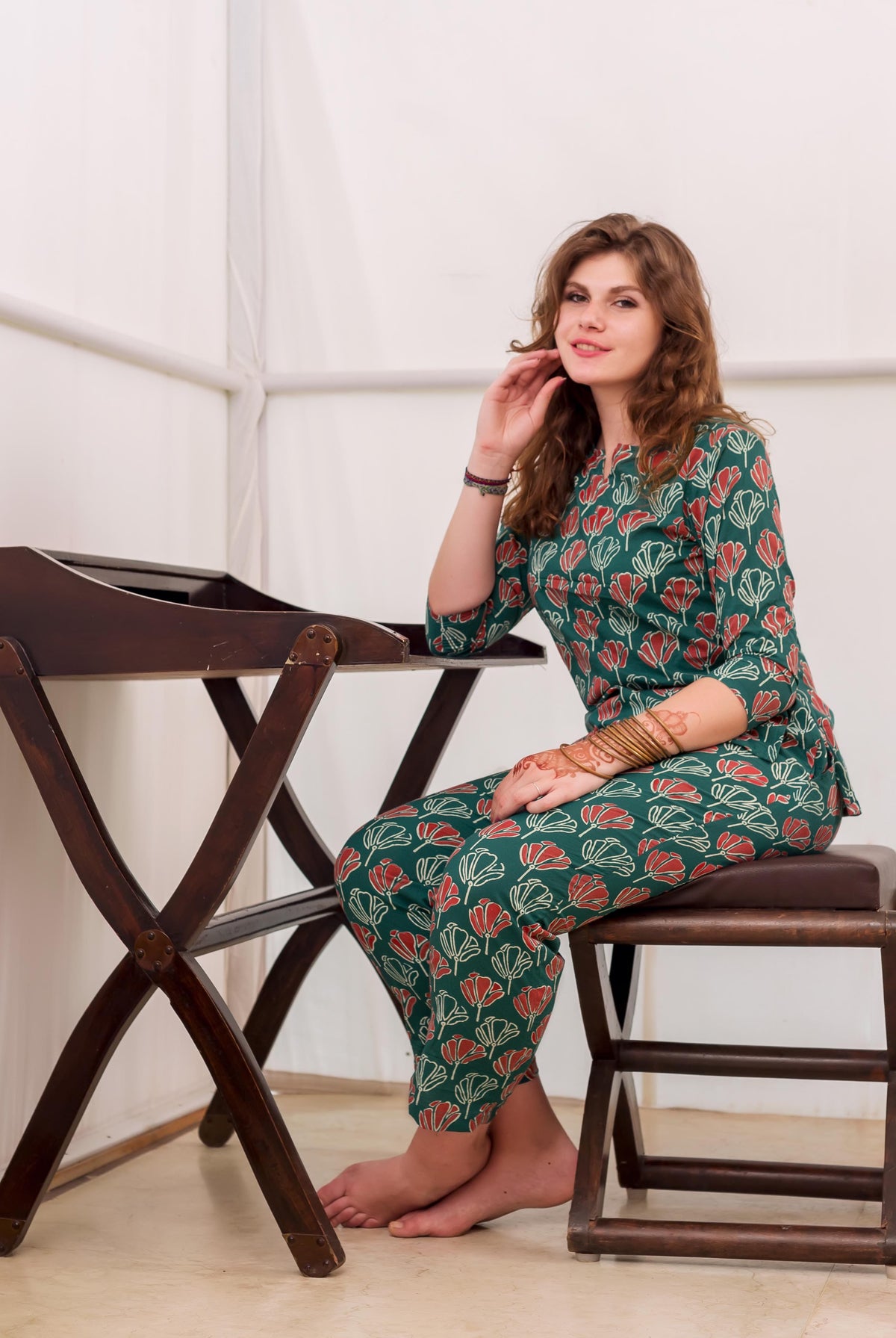 Smiling model seated in green and red block printed cotton night suit.