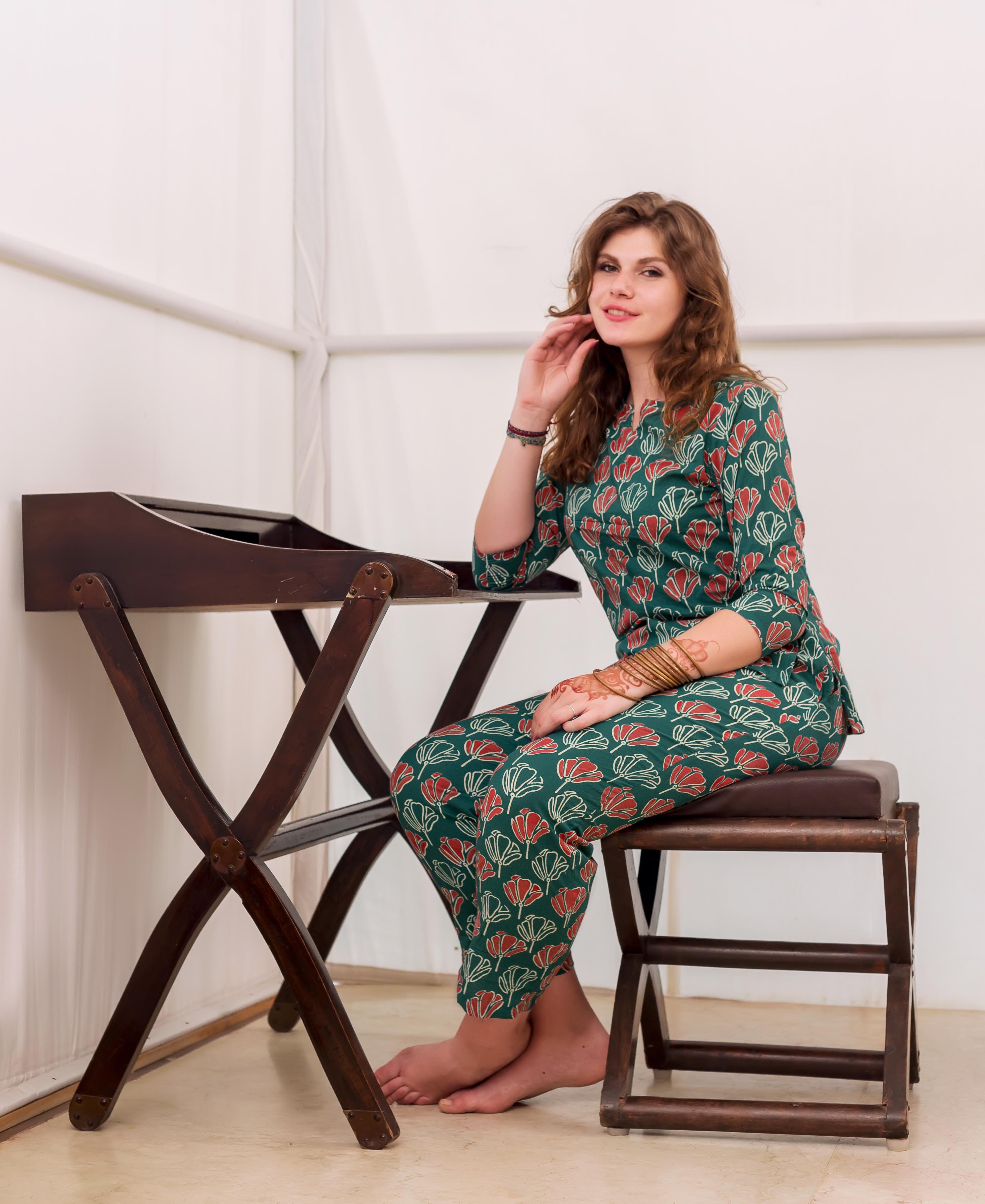 Smiling model seated in green and red block printed cotton night suit.