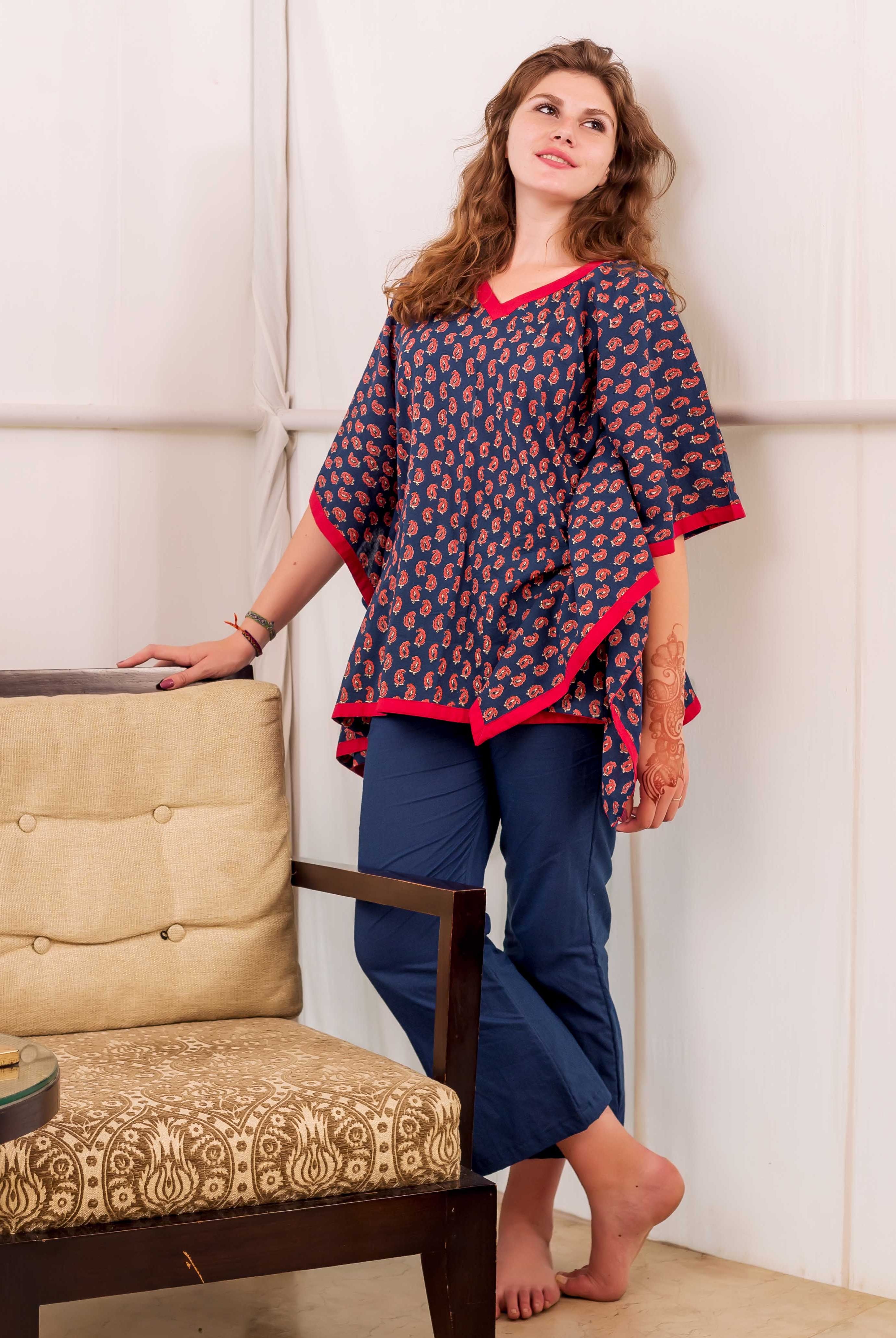 Front view of model wearing an indigo and red paisley print kaftan top with solid blue pants.