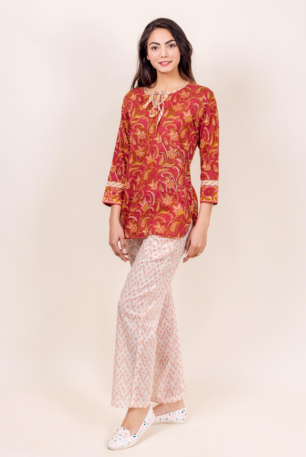Model wearing a rust and white block printed top and pajama set, full-body shot.