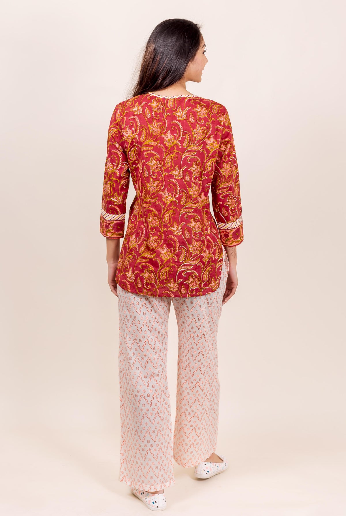 Back view of a woman in a rust block-printed top and white printed pajama.