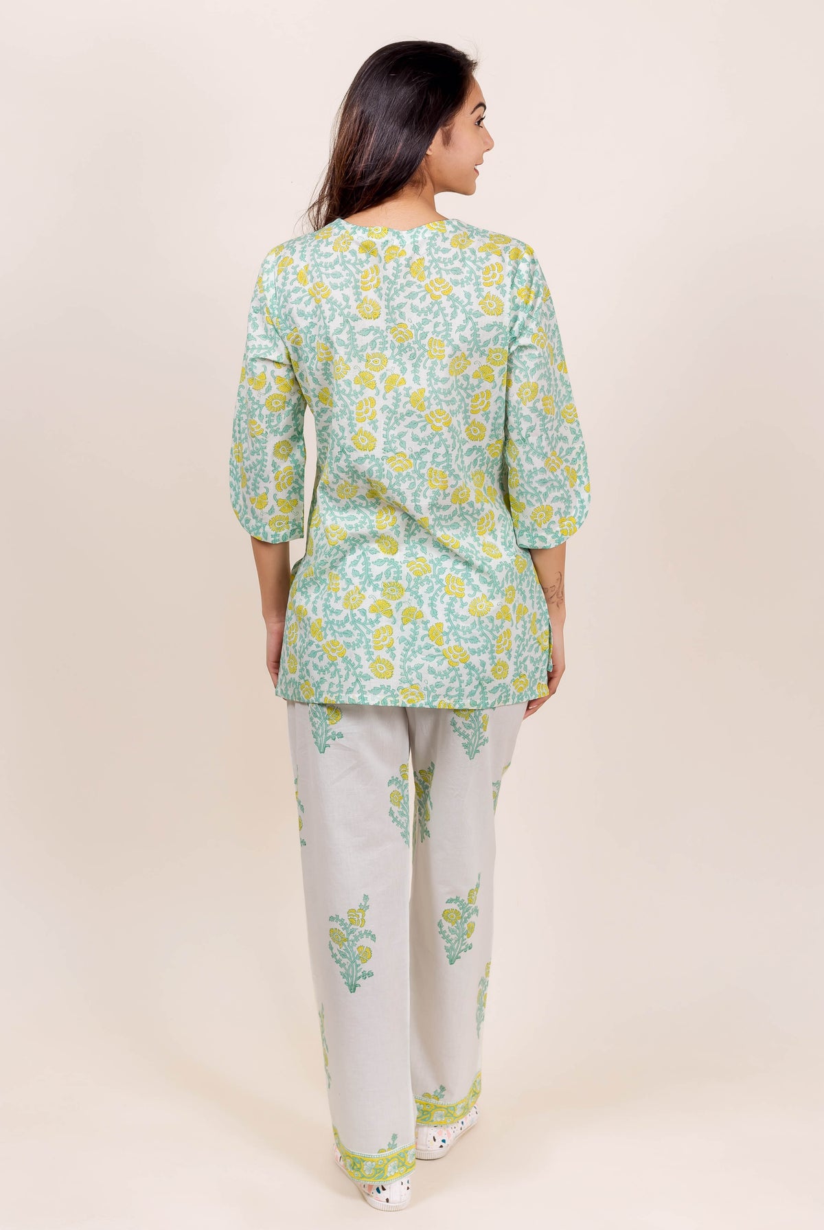 Back view of model wearing green and yellow floral block print top and white pajama set.