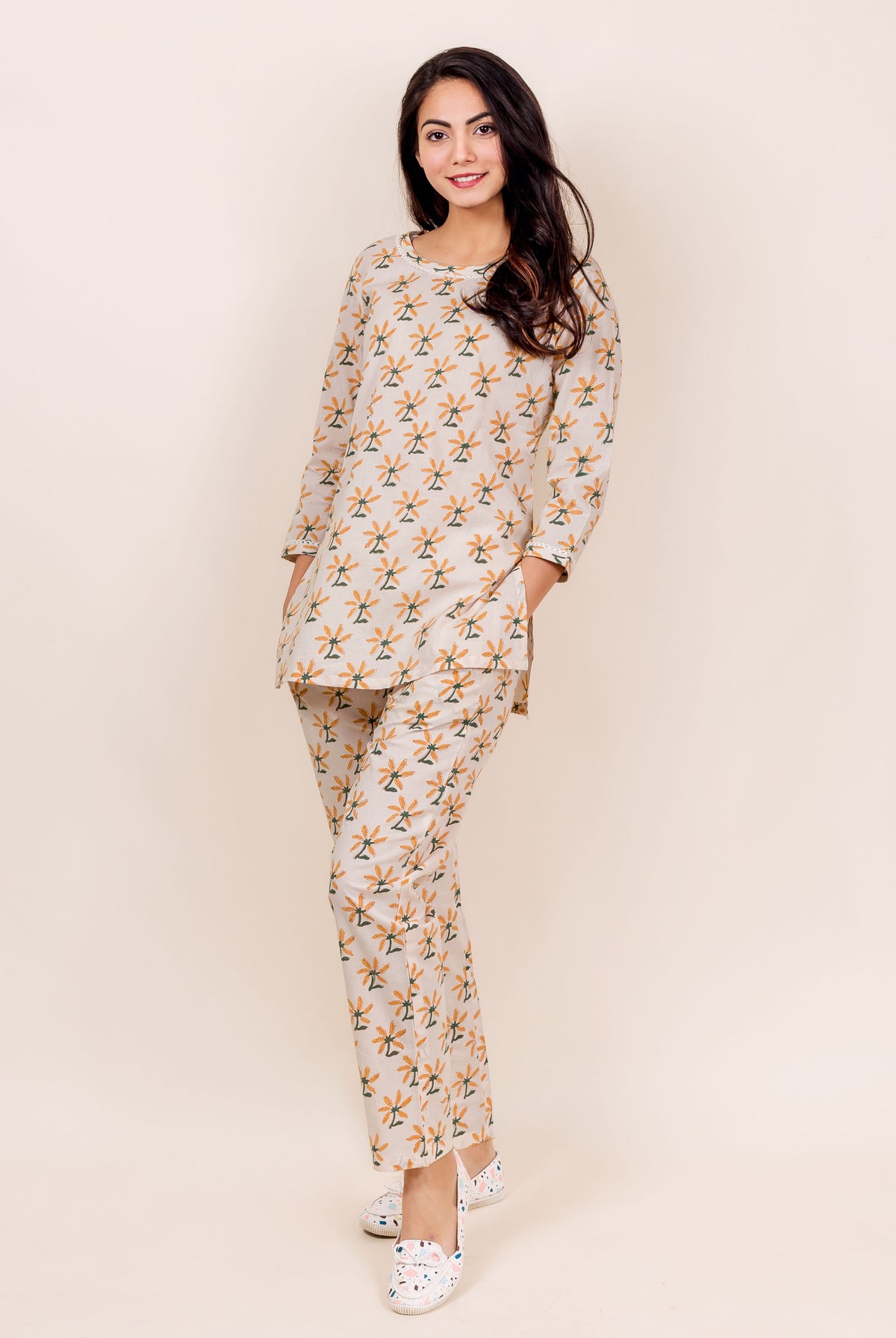 Model wearing front-facing beige block printed top and pajama set with floral motifs.