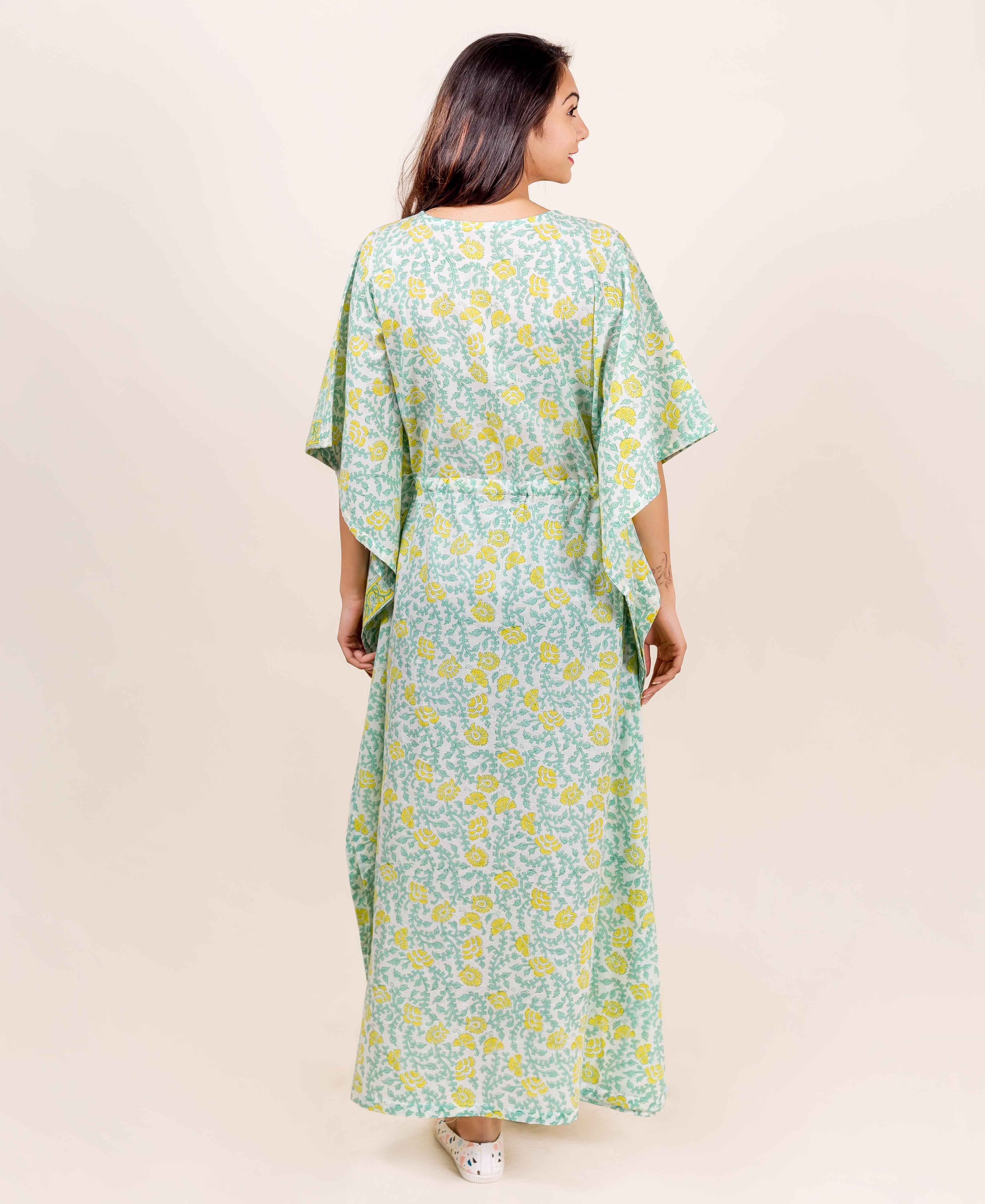 Back view of model wearing full-length mint green kaftan with yellow floral block print.