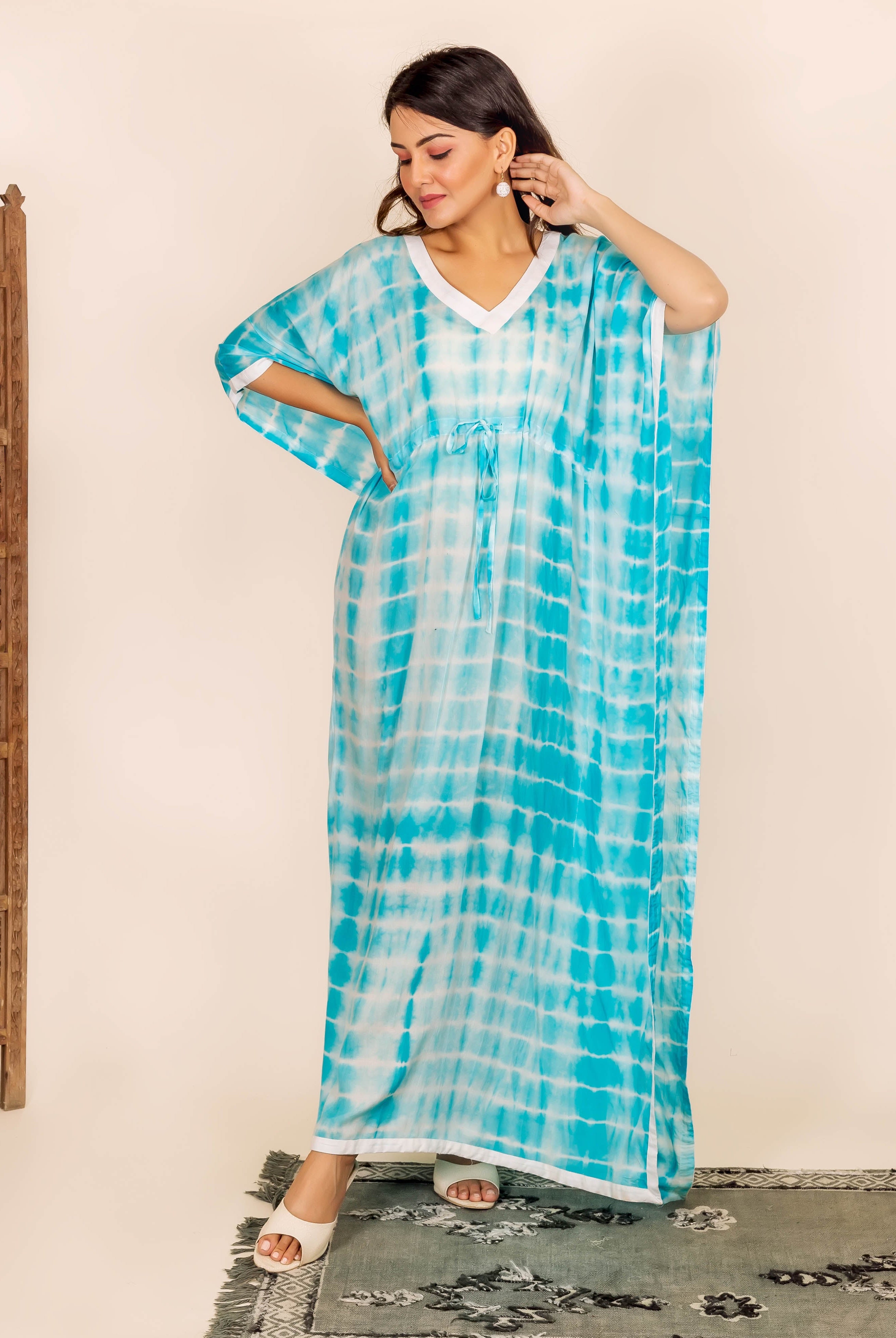 Woman in long blue and white tie-dye kaftan with adjustable waist and white trim.