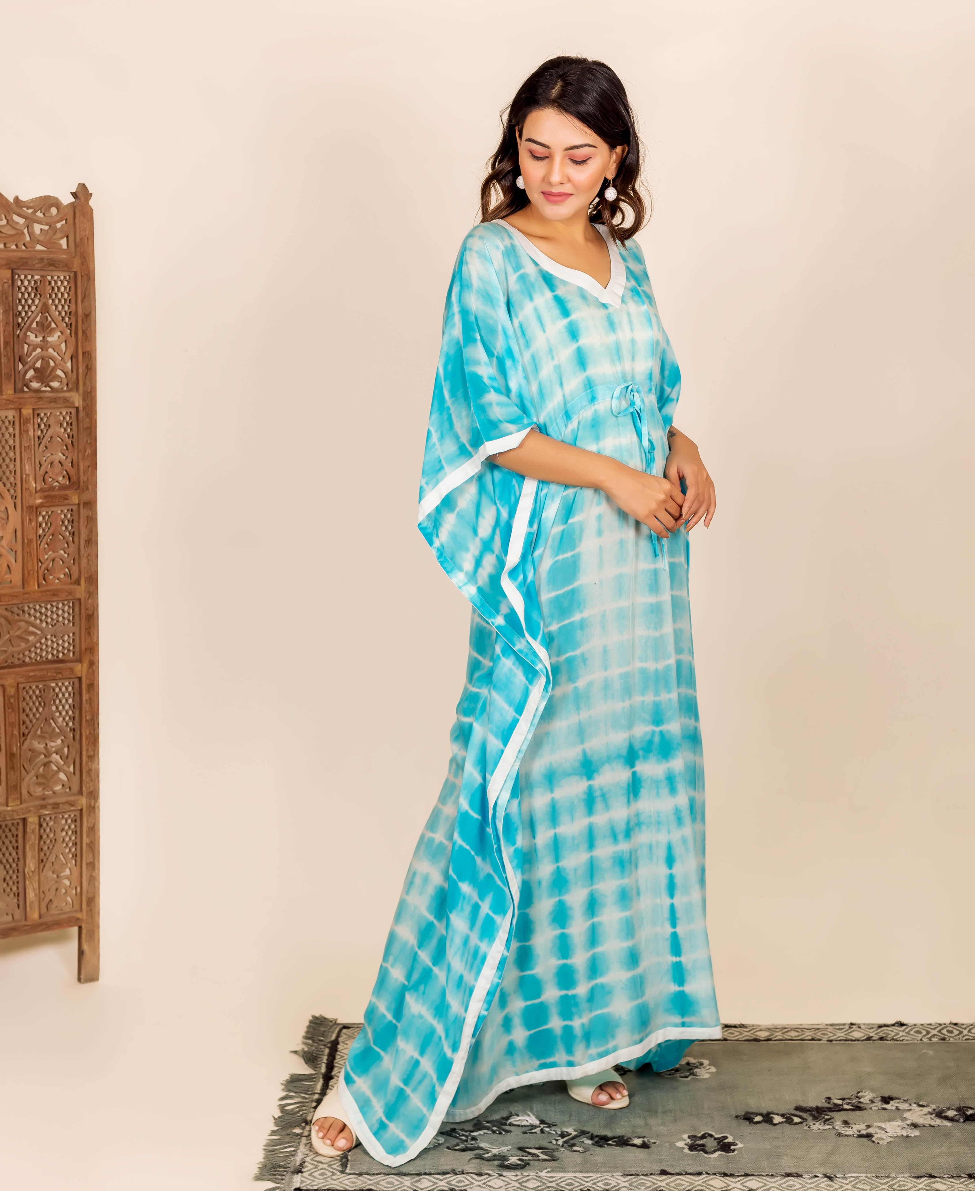 Woman wearing aqua and white tie-dye kaftan with adjustable waist line and white trim.
